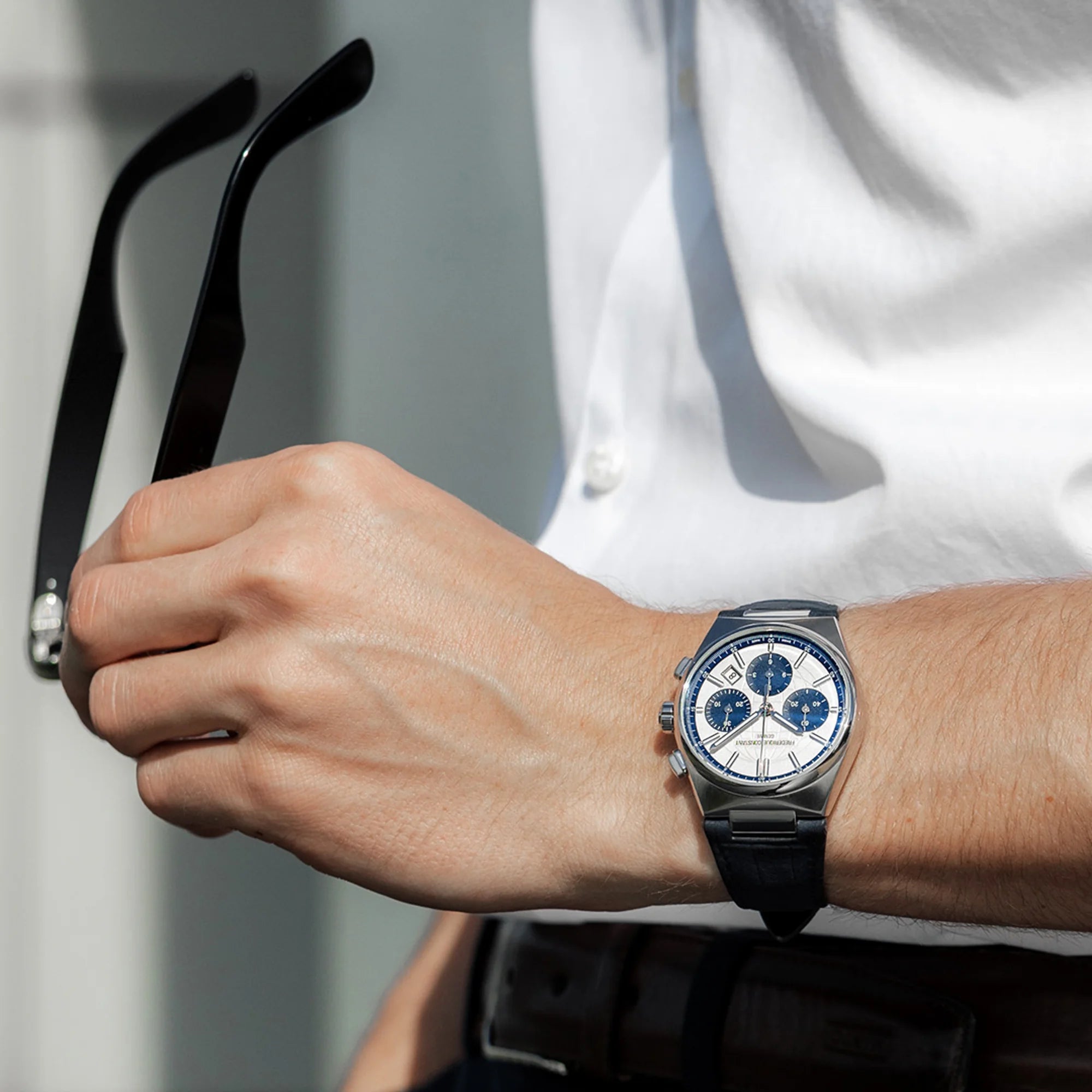 Wristhot des Automatic Chronographen mit blauen Akzenten und einem dunkelblauen Lederarmband von Frederique Constant aus der Highlife-Kollektion auf einem orangenen Hintergrund