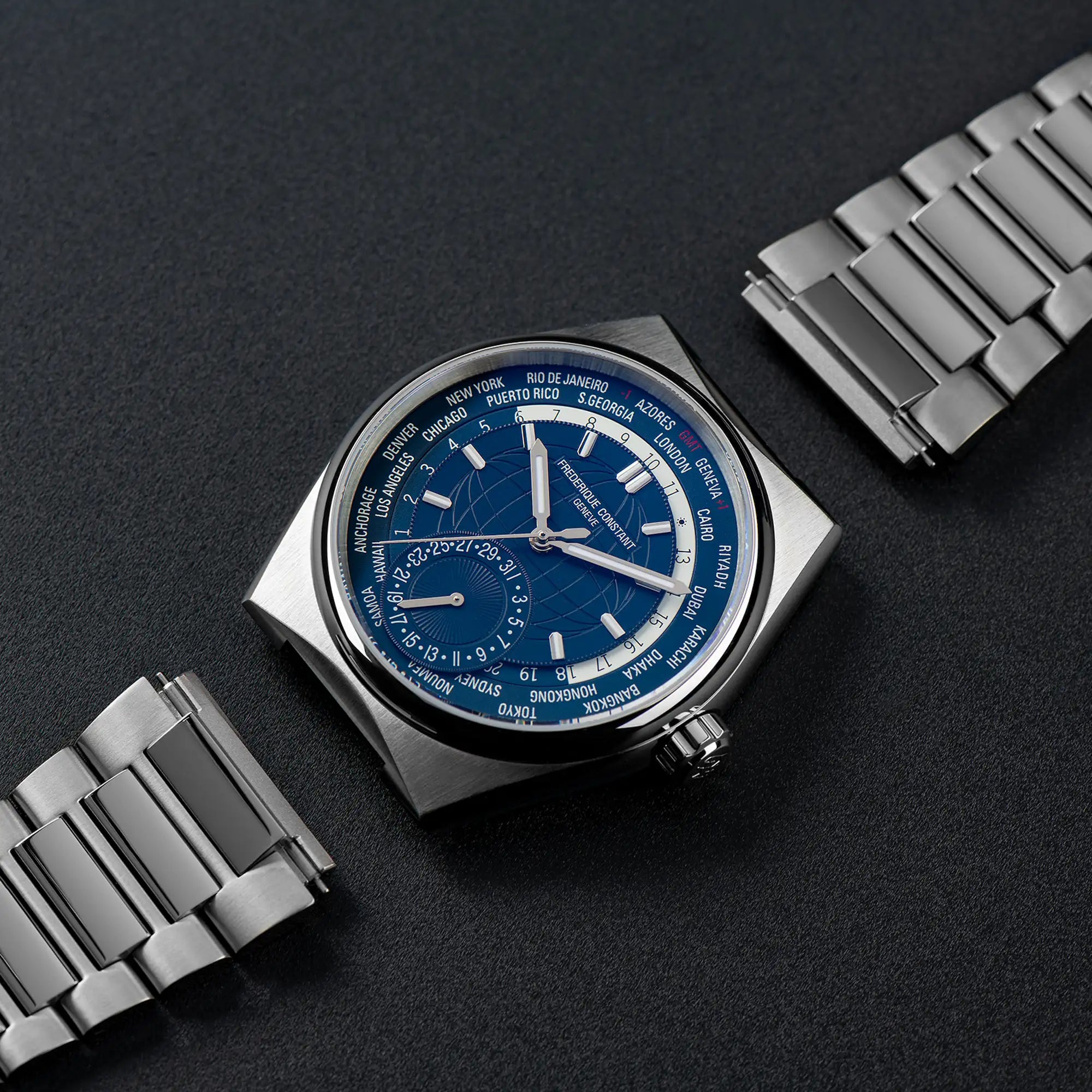 Produktfotografie der Worldtimer-Uhr von Frederique Constant aus der Highlife Kollektion mit einem blauen Zifferblatt, das verschiedene Städte und deren Zeitzonen zeigen kann, an die das Edelstahl-Armband mit dem Schnellwechselsystem noch angebracht werden muss