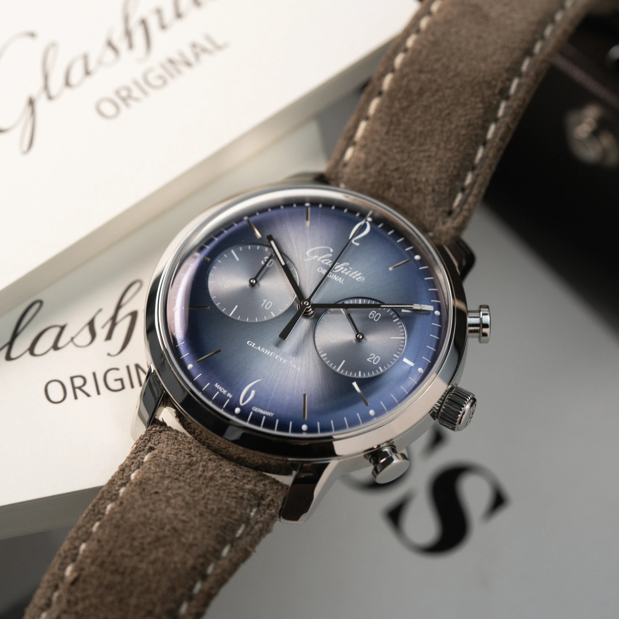 Liegende Glashütte Original Sixties Chronograph mit Fokus auf dem blauen Sonnenschliff-Zifferblatt