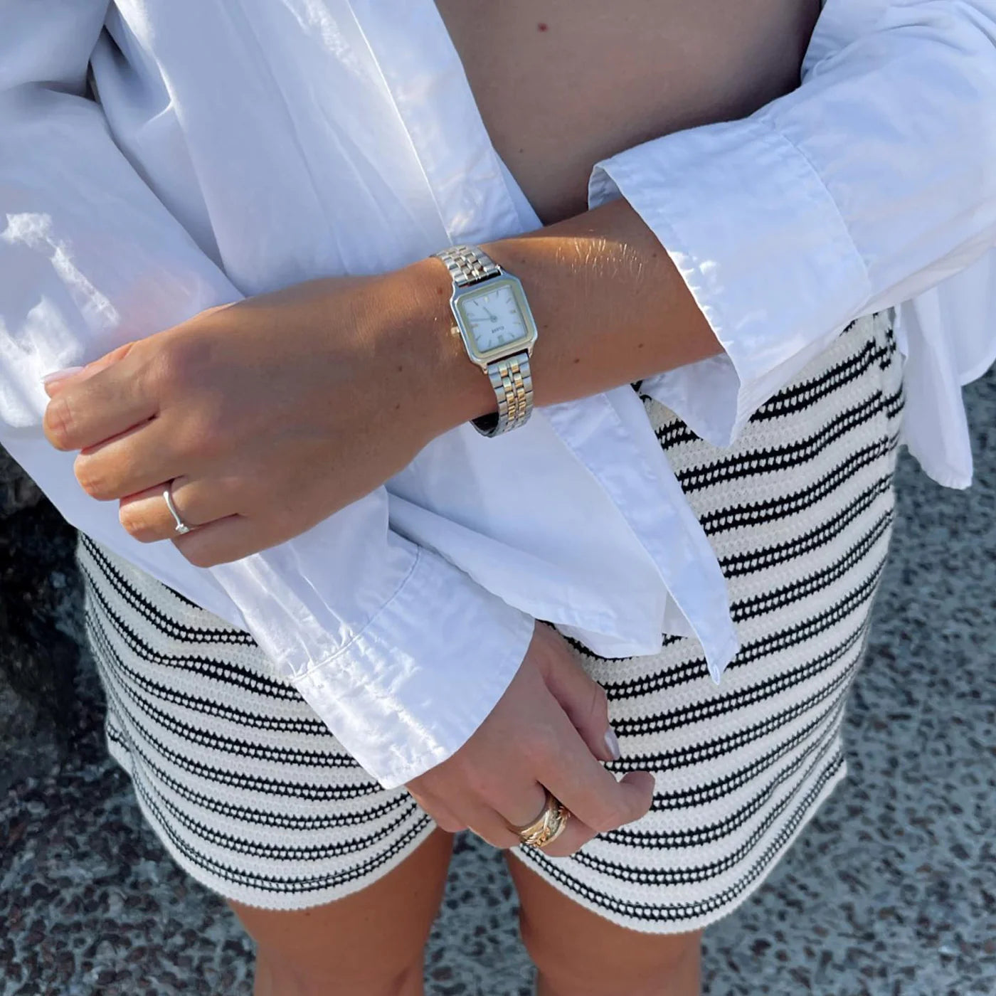 Frau trägt ein sommerliches Outfit und die  Cluse Stahl-Uhr "Gracieuse Petite" in Stahl-Gold-Optik (bicolor) mit weißem Zifferblatt an ihrem Handgelenk
