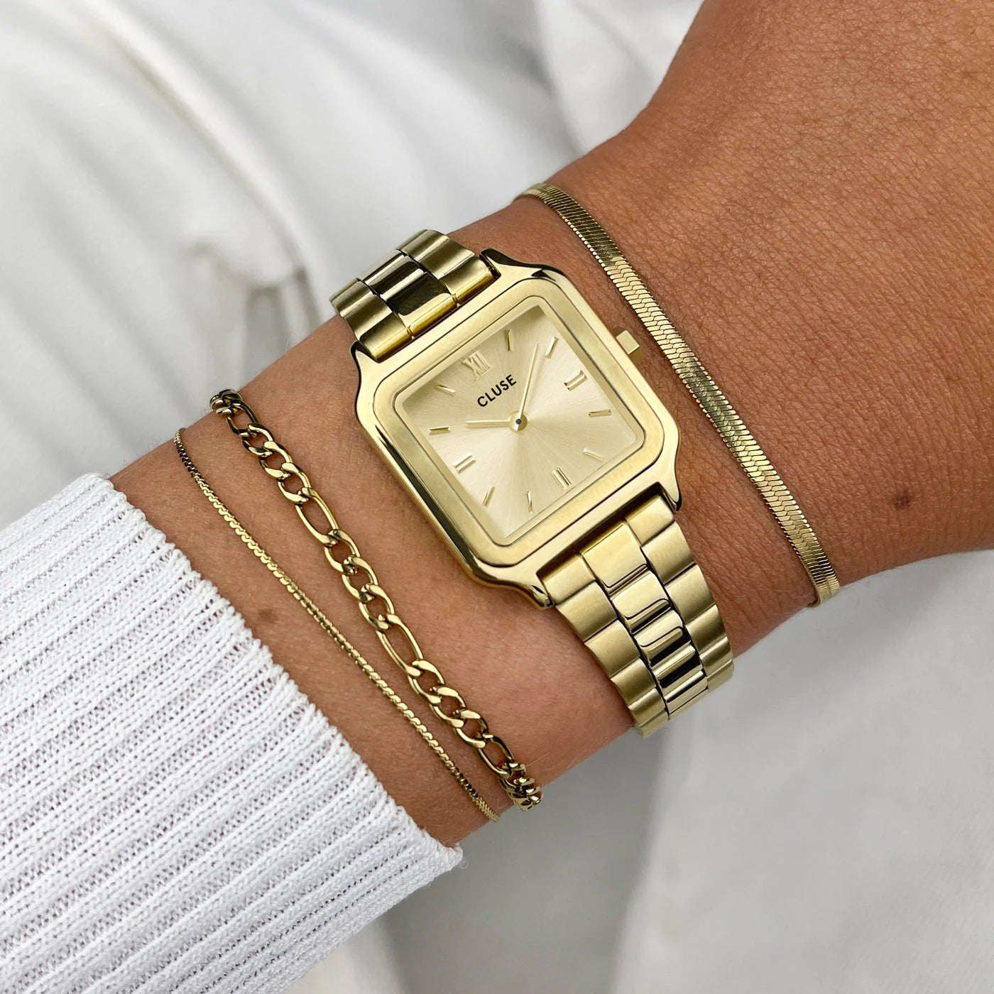 Wristshot an einem Frauenhandgelenk mit der Cluse Stahl-Uhr "Gracieuse Petite" mit einem gelbgold-farbenem Gehäuse und Zifferblatt