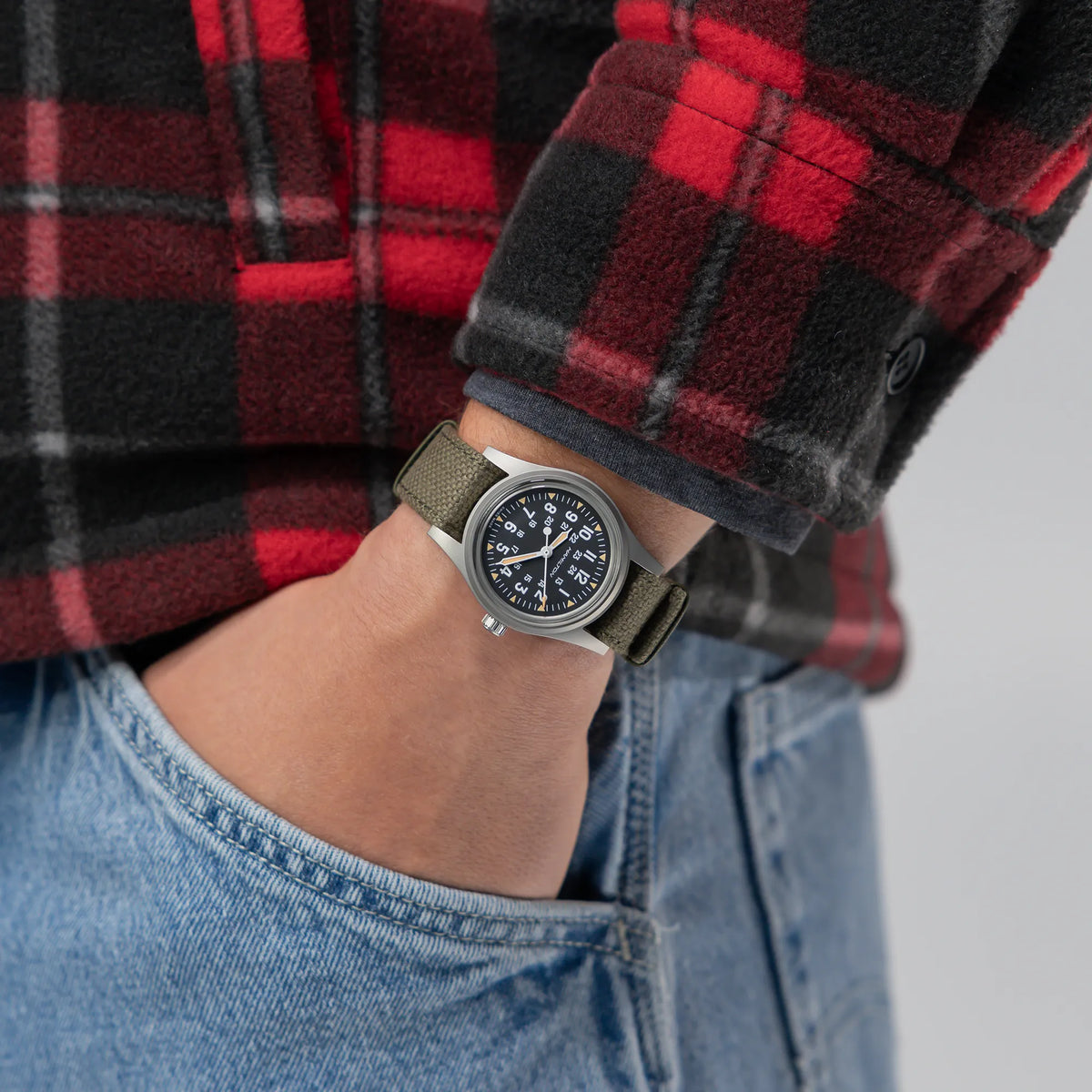 Wristshot mit der Hamilton Khaki Field Mechanical H69399930 mit schwarzem Zifferblatt im Vintage-Charakter mit Indizes in weiß und beige an einem khaki-farbenem Nato-Band