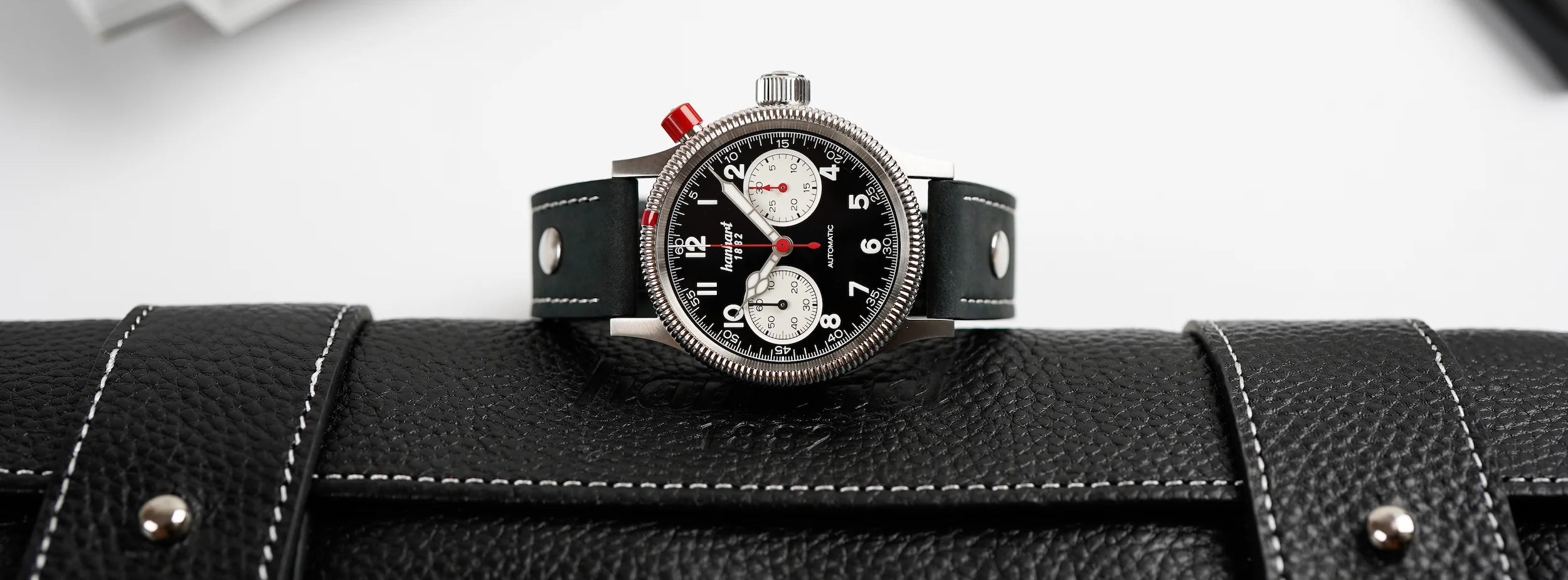 Hanahrt Pioneer MK1 mit dem Reverse Panda Zifferblatt liegt quer auf der ledernen Verpackung