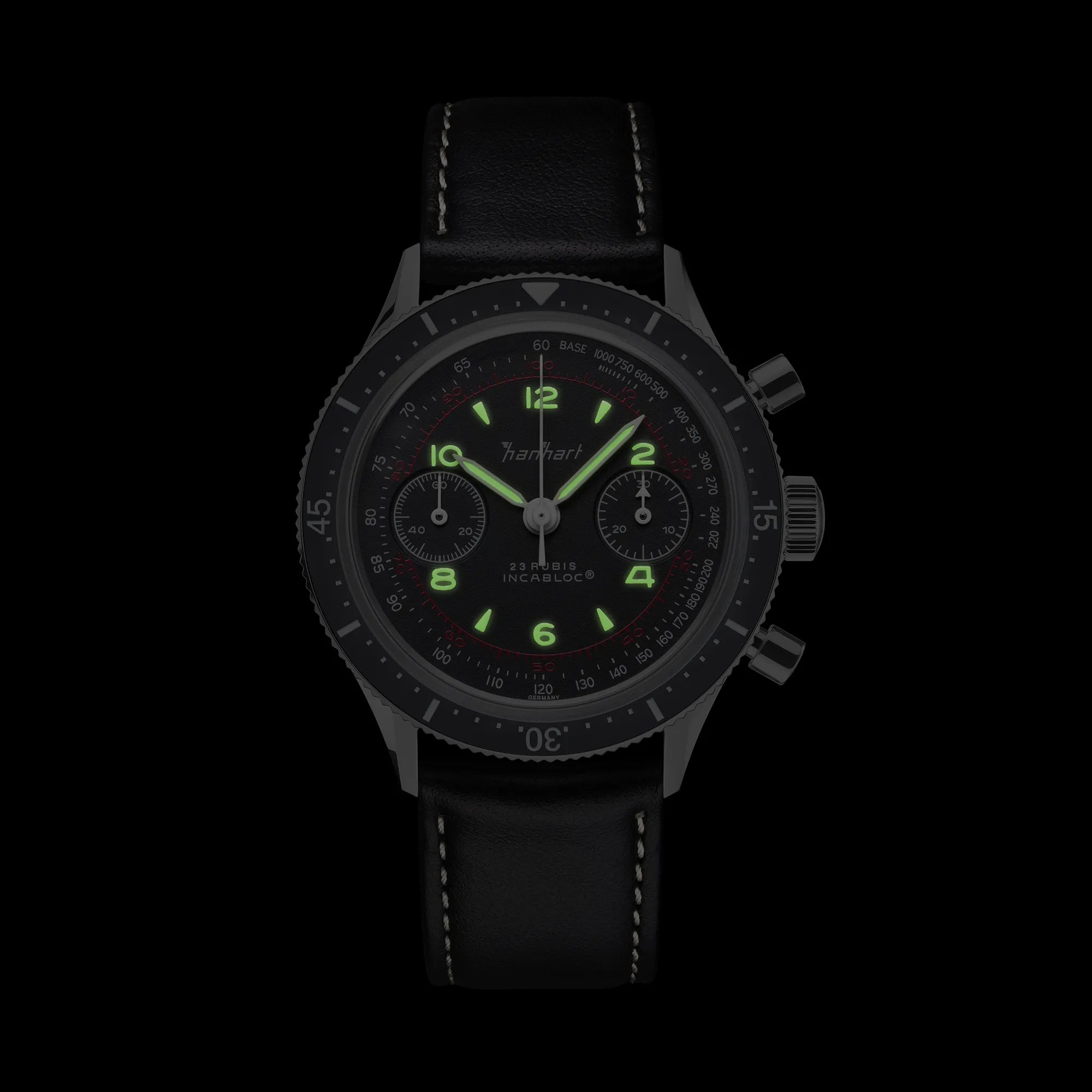 Frontale Ansicht des Hanhart 415 ES Pure Chronographen in Edelstahl mit weißen und roten Details am Lederband bei Nacht mit leuchtenden Zeigern und Indizes