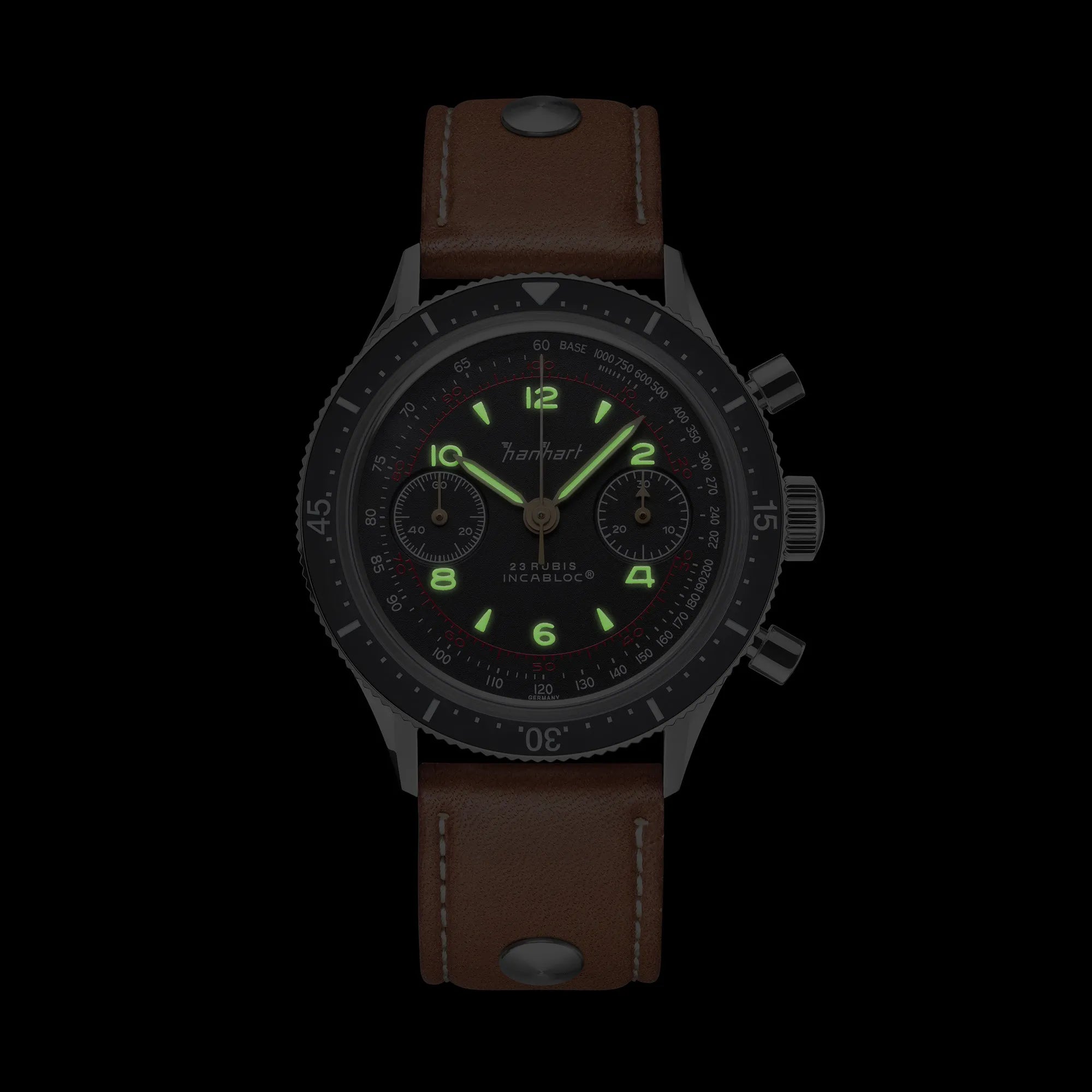 Frontale Ansicht des klassischen Hanhart Chronographs "415 ES" an einem braunen Lederband bei Nacht mit leuchtenden Zeigern und Indizes