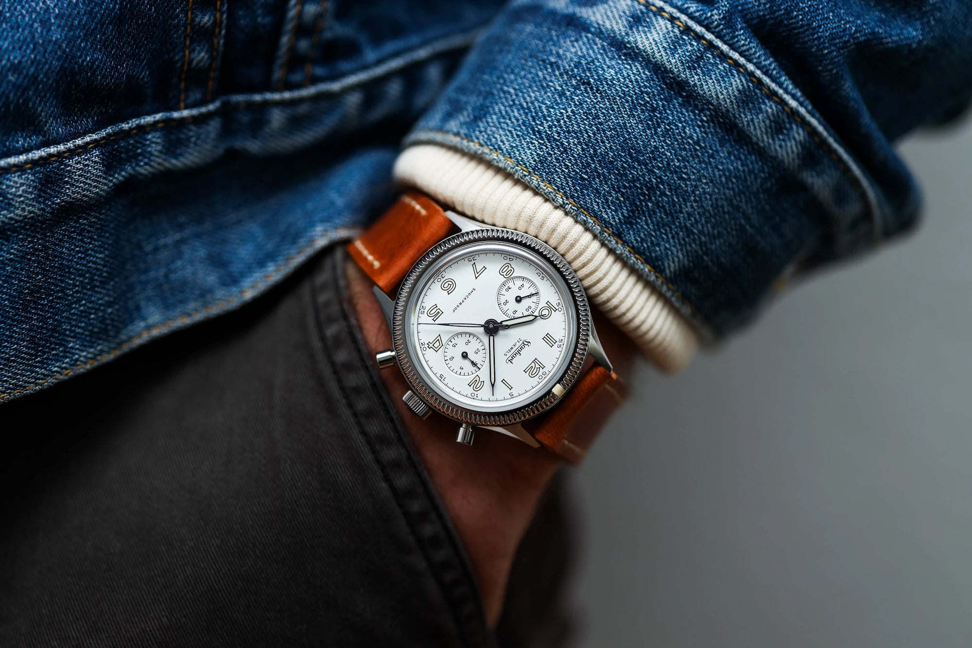 Mann trägt den Hanhart 417 ES "Moby Dick" Chronograph mit 42mm-Gehäuse und weißem Zifferblatt am hellbraunen Lederband an seinem Handgelenk