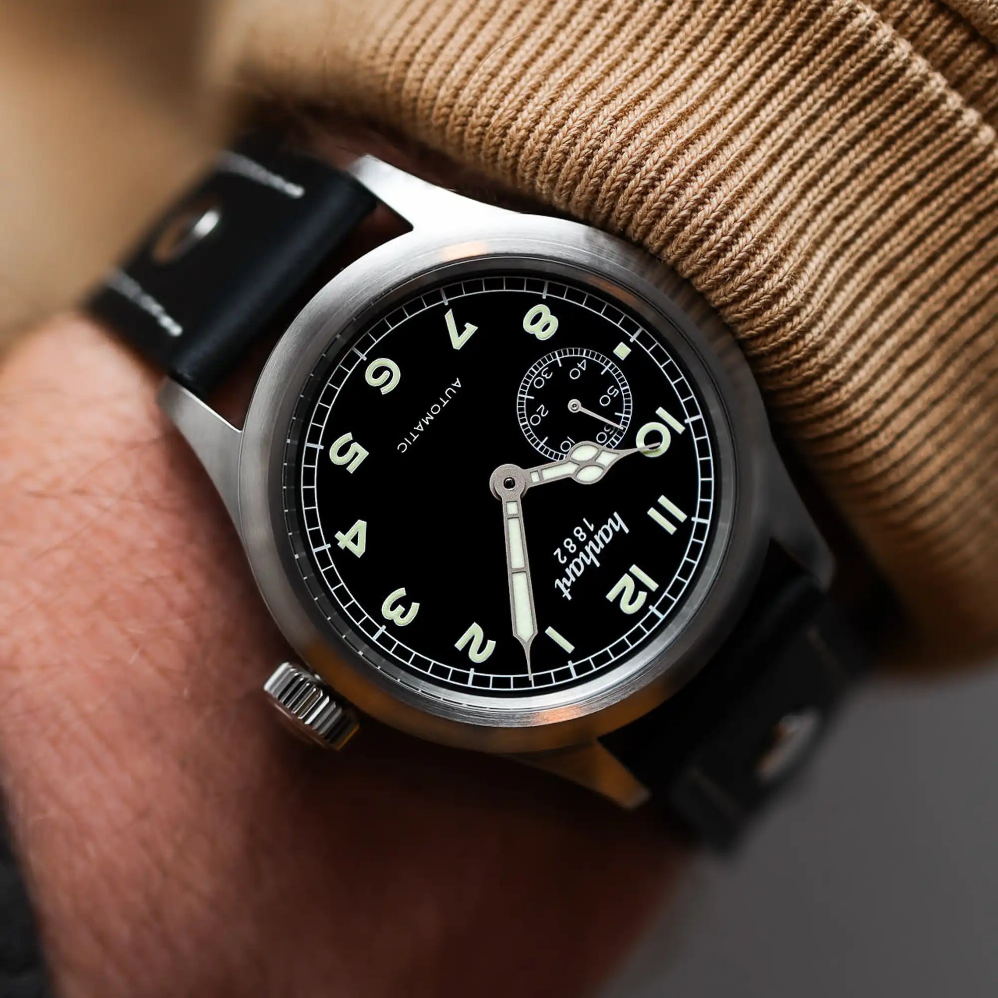 Mann trägt die Hanhart Pioneer Preventor9 aus Edelstahl mit einem schwarzen Zifferblatt und einem schwarzen Lederband