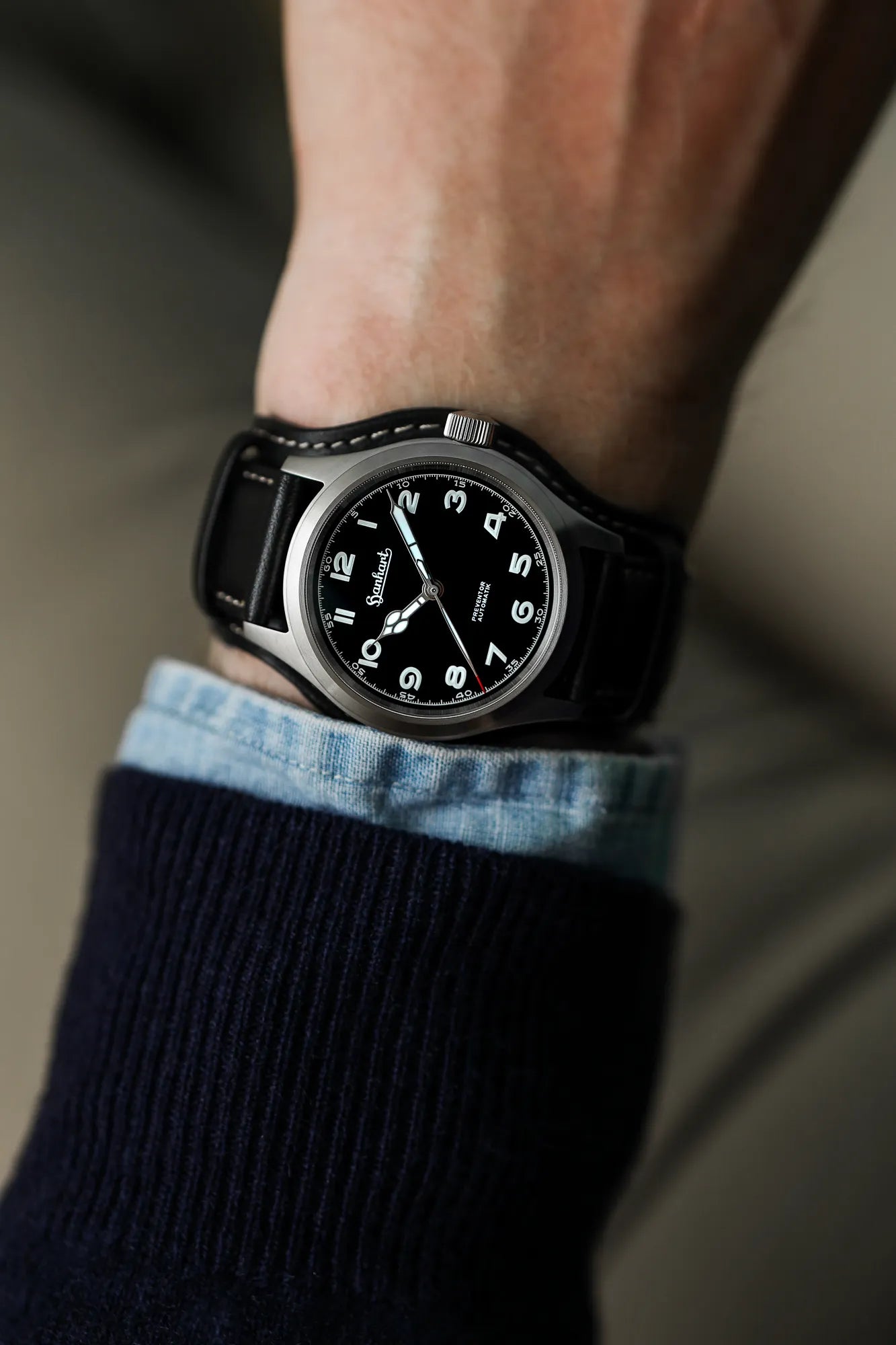 Mann trägt die Hanhart Preventor HD12 Dreizeiger-Uhr mit schwarzem Zifferblatt an seinem Handgelenk