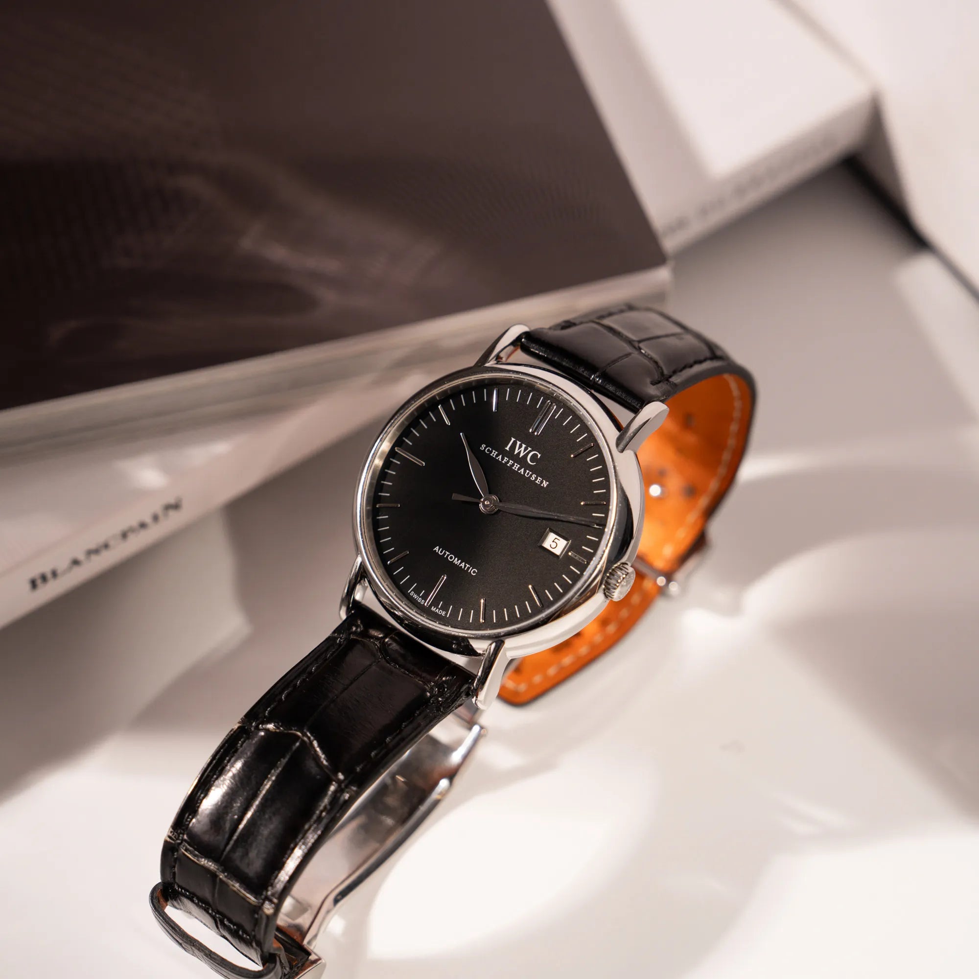 Produkfoto zeigt das Lederband und den Uhrenkopf der IWC Portofino Automatik IW356305 Armbanduhr mit minimalistischen, schwarzem Zifferblatt mit Stichindizes am schwarzen Lederband