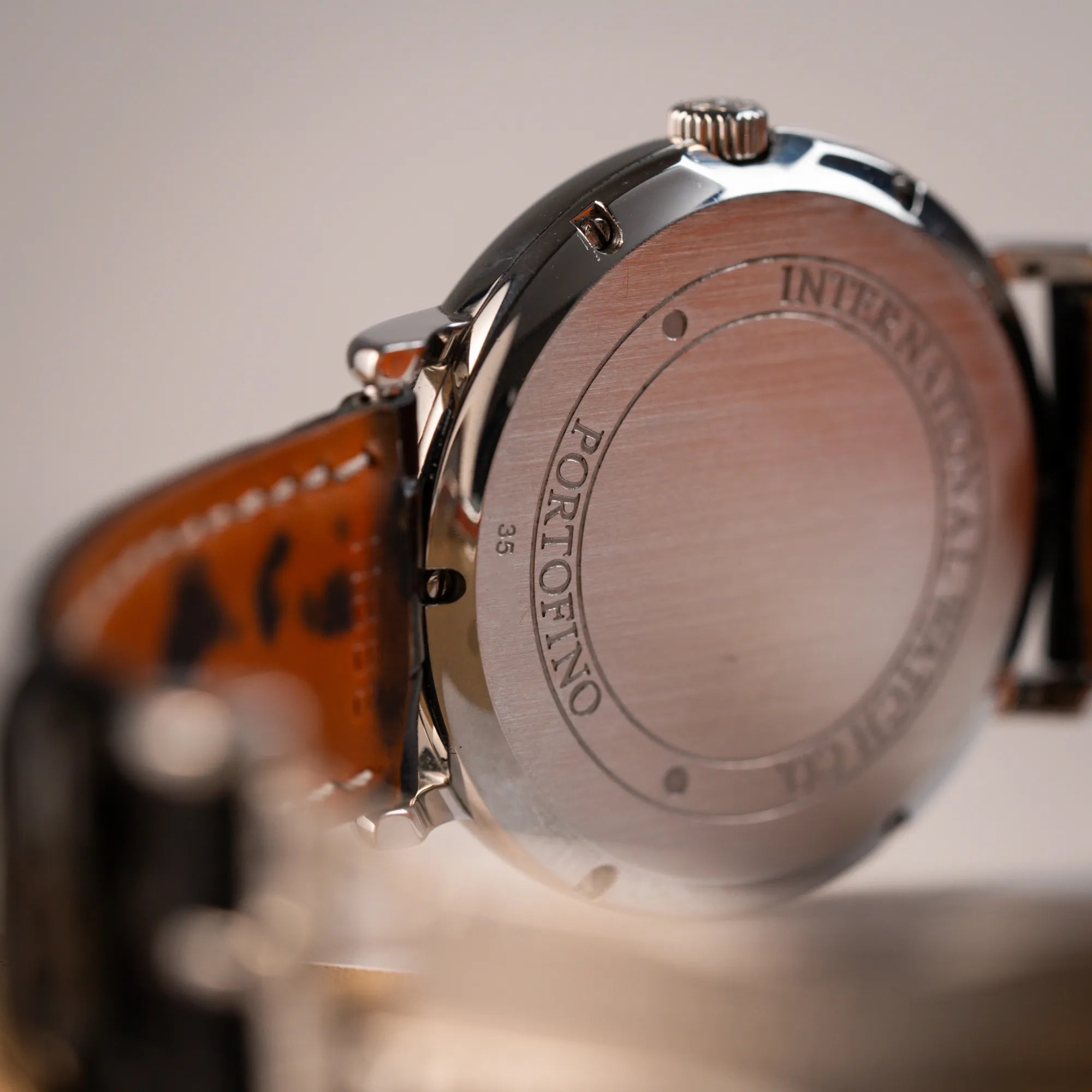 Produktfotografie zeigt den Gehäuseboden der IWC Portofino Automatik IW356305 Armbanduhr mit minimalistischen, schwarzem Zifferblatt mit Stichindizes am schwarzen Lederband