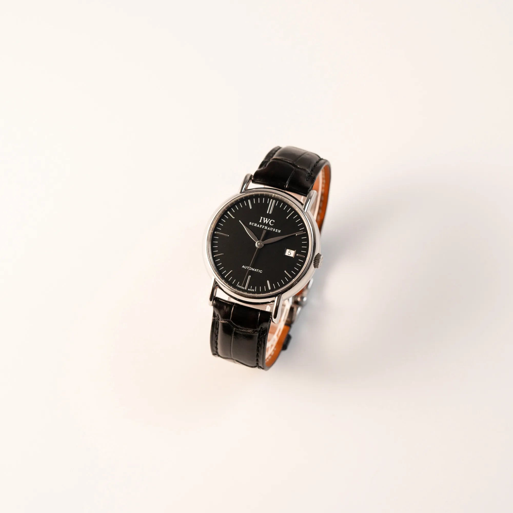 Leicht schräge Ansicht der IWC Portofino Automatik IW356305 Armbanduhr mit minimalistischen, schwarzem Zifferblatt mit Stichindizes am schwarzen Lederband