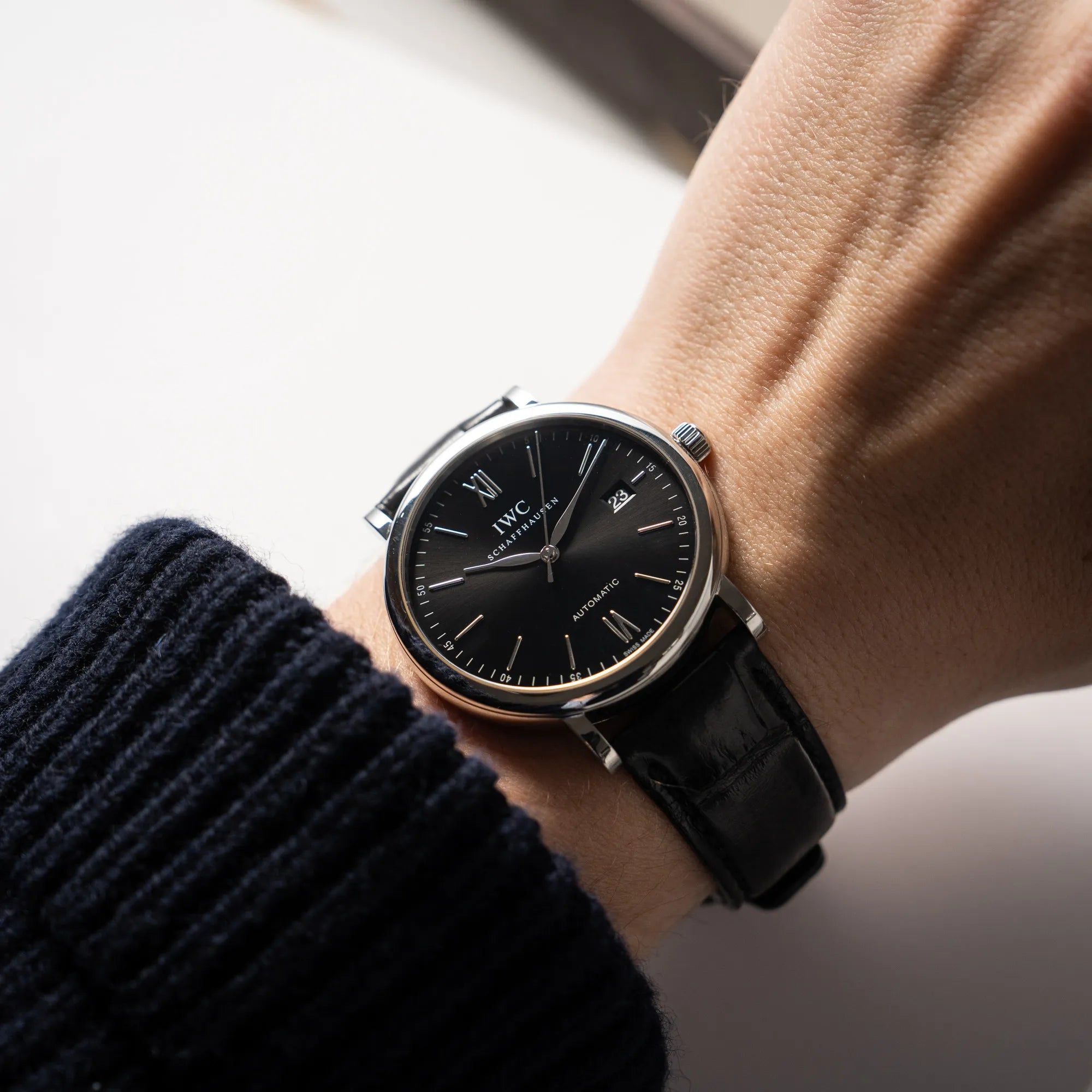 Mann trägt die IWC Portofino 40 Automatik Armbanduhr mit schwarzem Zifferblatt am schwarzen Lederband an seinem Handgelenk