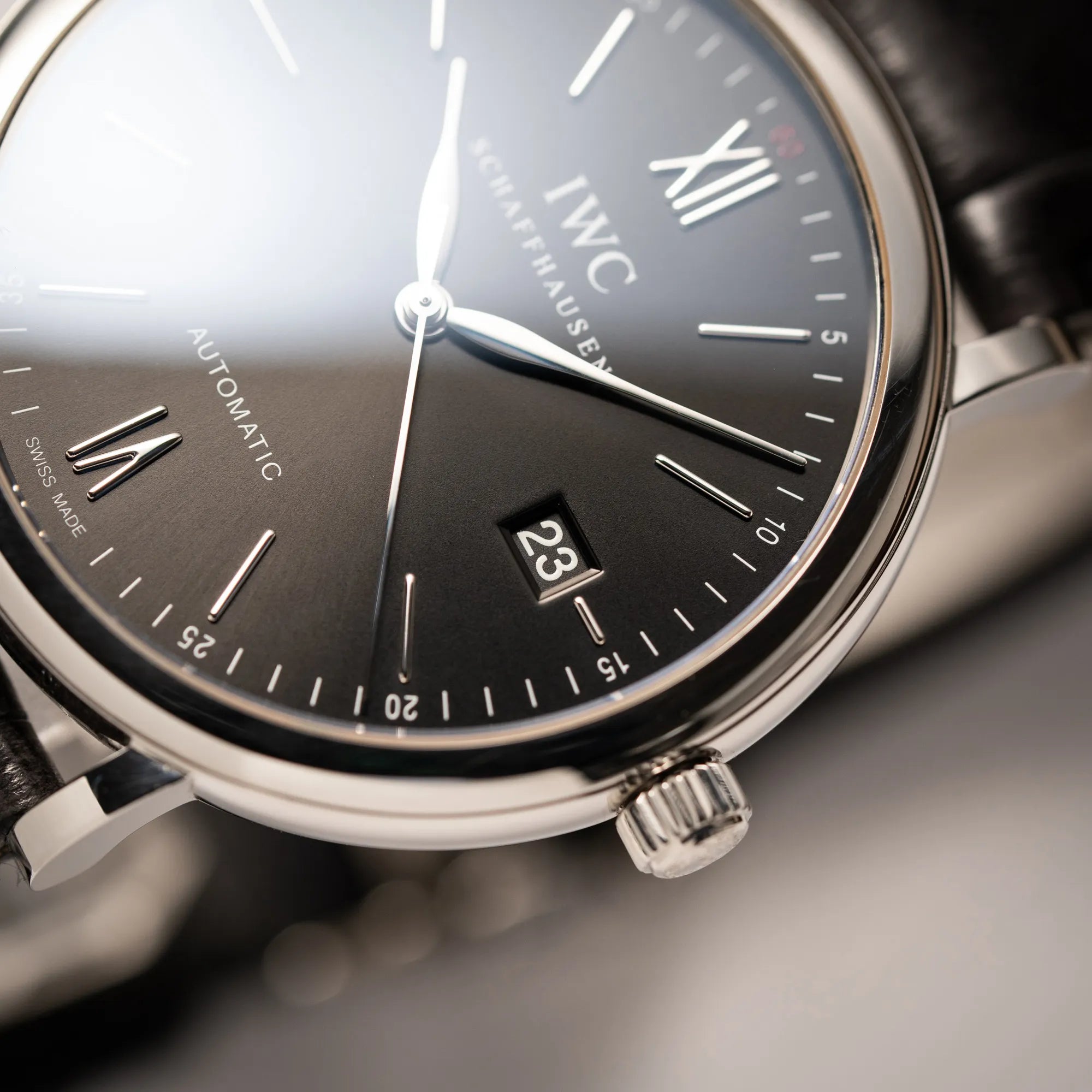 Detailaufnahme der IWC Portofino 40 Automatik Armbanduhr mit schwarzem Zifferblatt am schwarzen Lederband mit Fokus auf der Datumsanzeige bei 3 Uhr