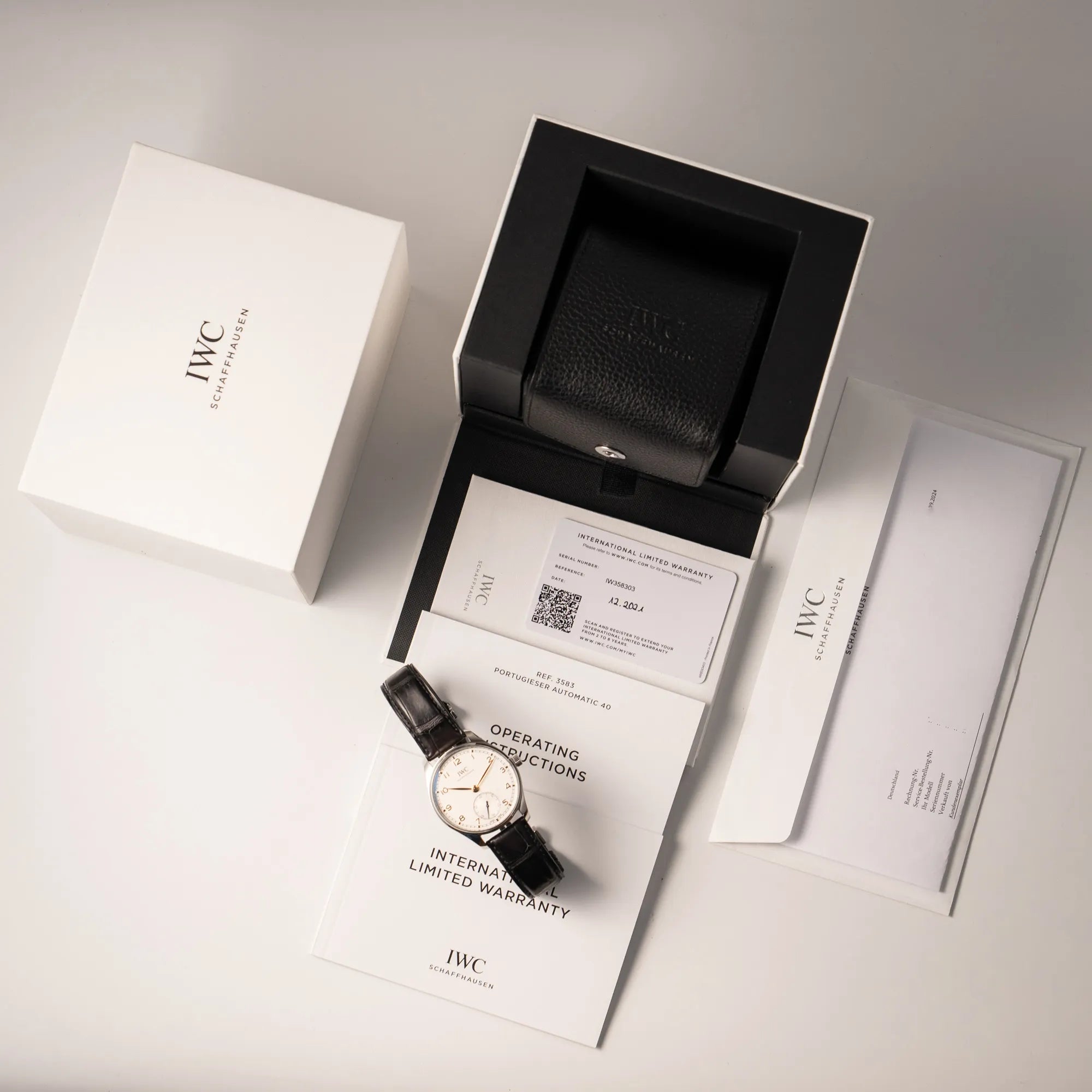 Lieferumfang zu der IWC Portugieser 40 Automatik IW358303 mit weißem Zifferblatt und roségoldenen Zeiger- und Index-Details am schwarzen Lederband bestehend aus Box mit Umkarton, original Papieren und allen Booklets