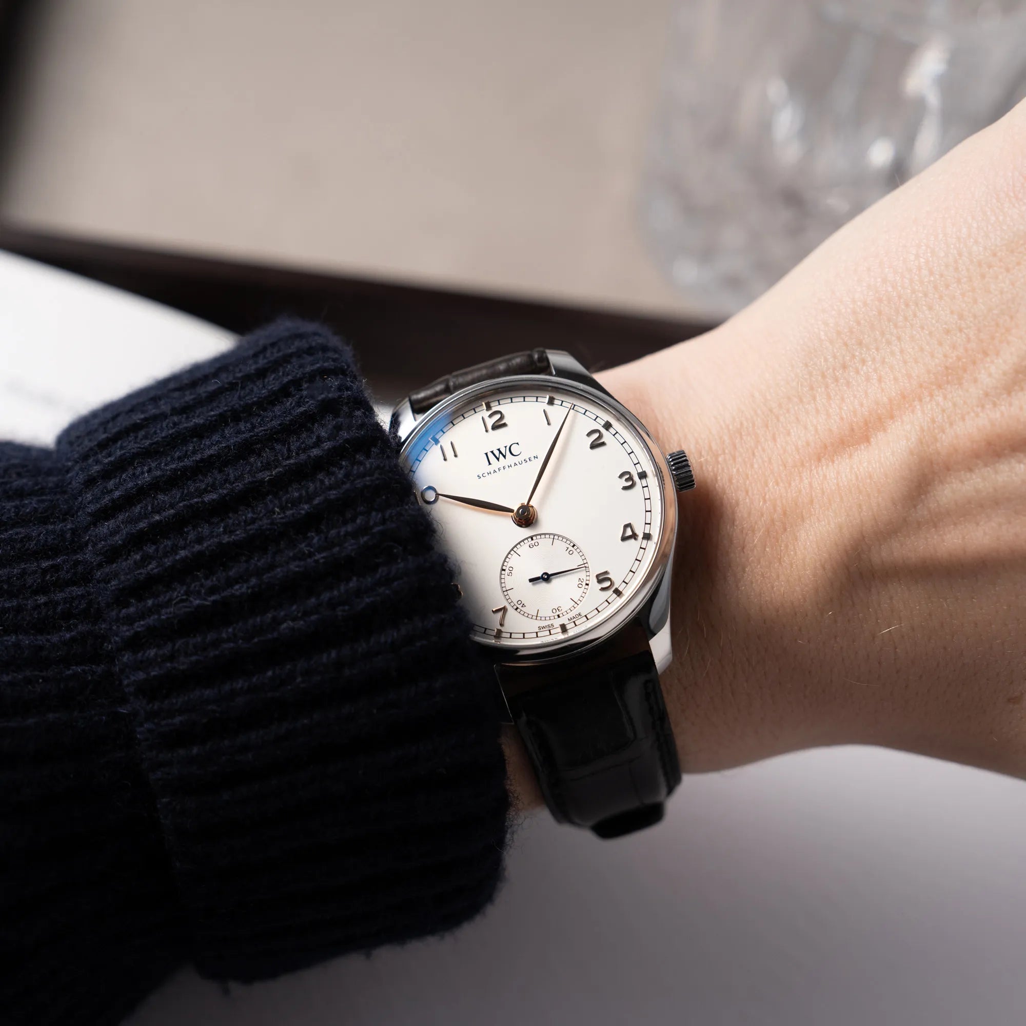 IWC Portugieser 40 Automatik IW358303 mit weißem Zifferblatt und roségoldenen Zeiger- und Index-Details am schwarzen Lederband getragen an einem Männerhandgelenk