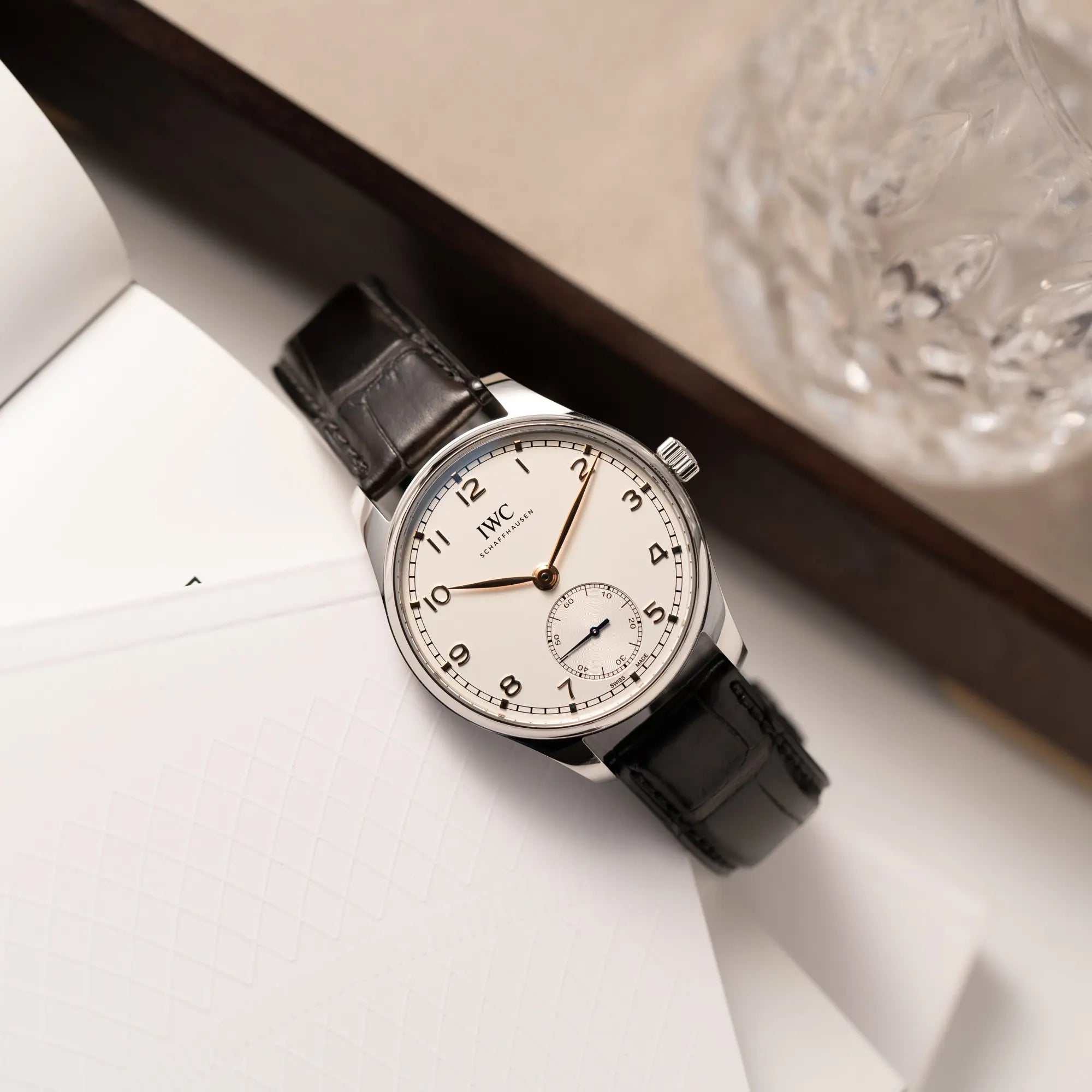 Produktfotografie der IWC Portugieser 40 Automatik IW358303 mit weißem Zifferblatt und roségoldenen Zeiger- und Index-Details am schwarzen Lederband