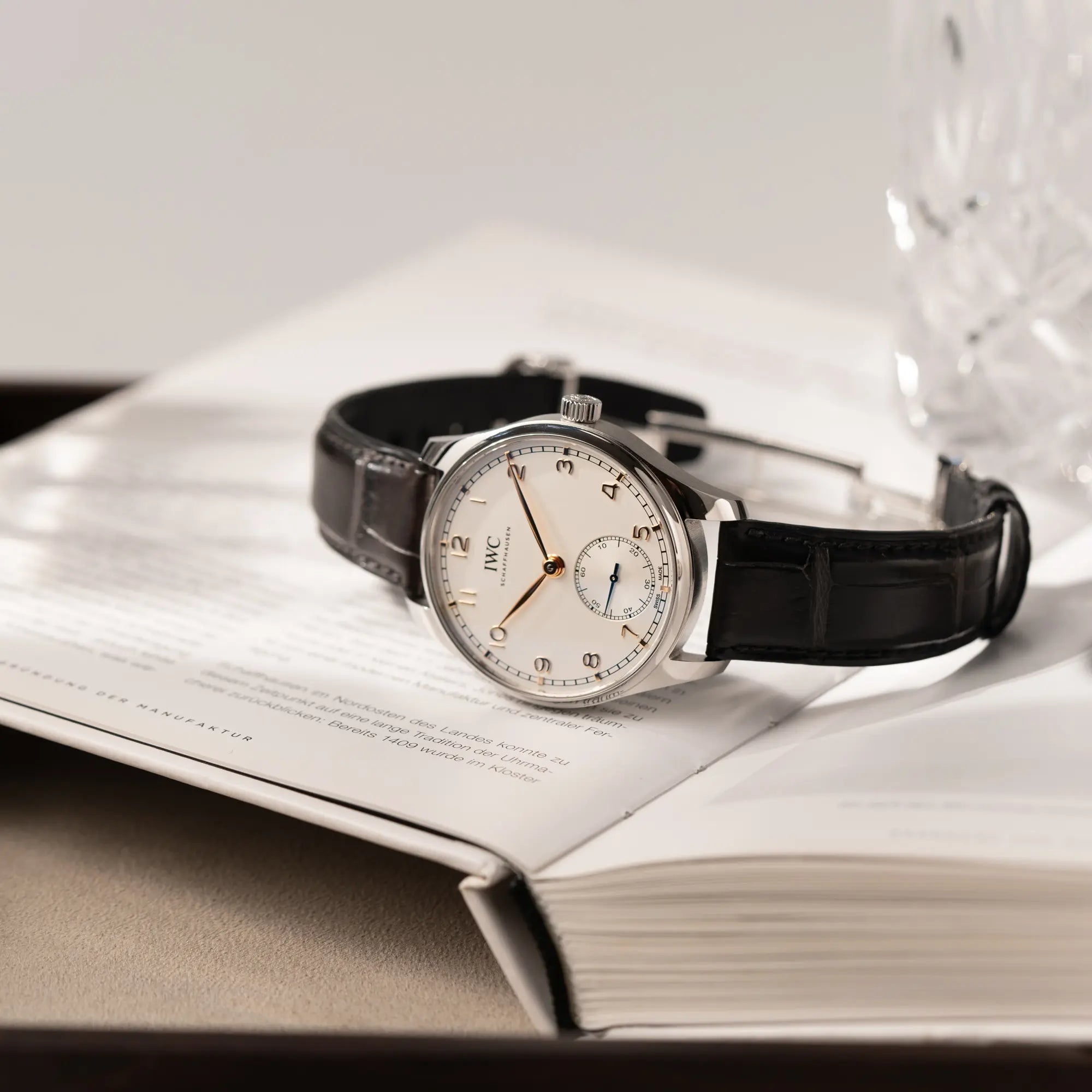 Produktfotografie der IWC Portugieser 40 Automatik IW358303 mit weißem Zifferblatt und roségoldenen Zeiger- und Index-Details am schwarzen Lederband