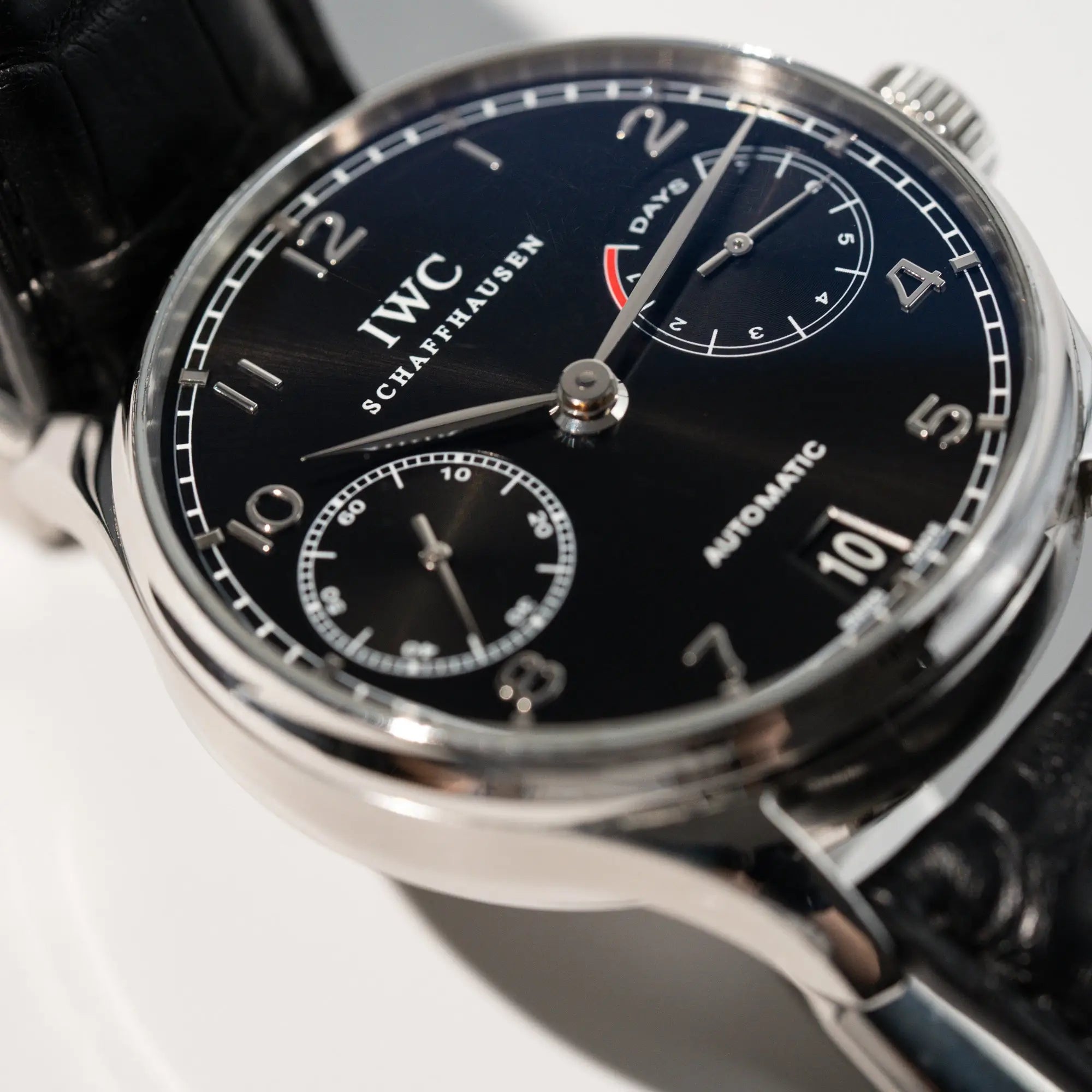 Detailaufnahme der Portugieser 7 Days Automatic IW500109 Uhr von IWC Schaffhausen am schwarzen Lederband mit Fokus auf dem schwarzen Zifferblatt