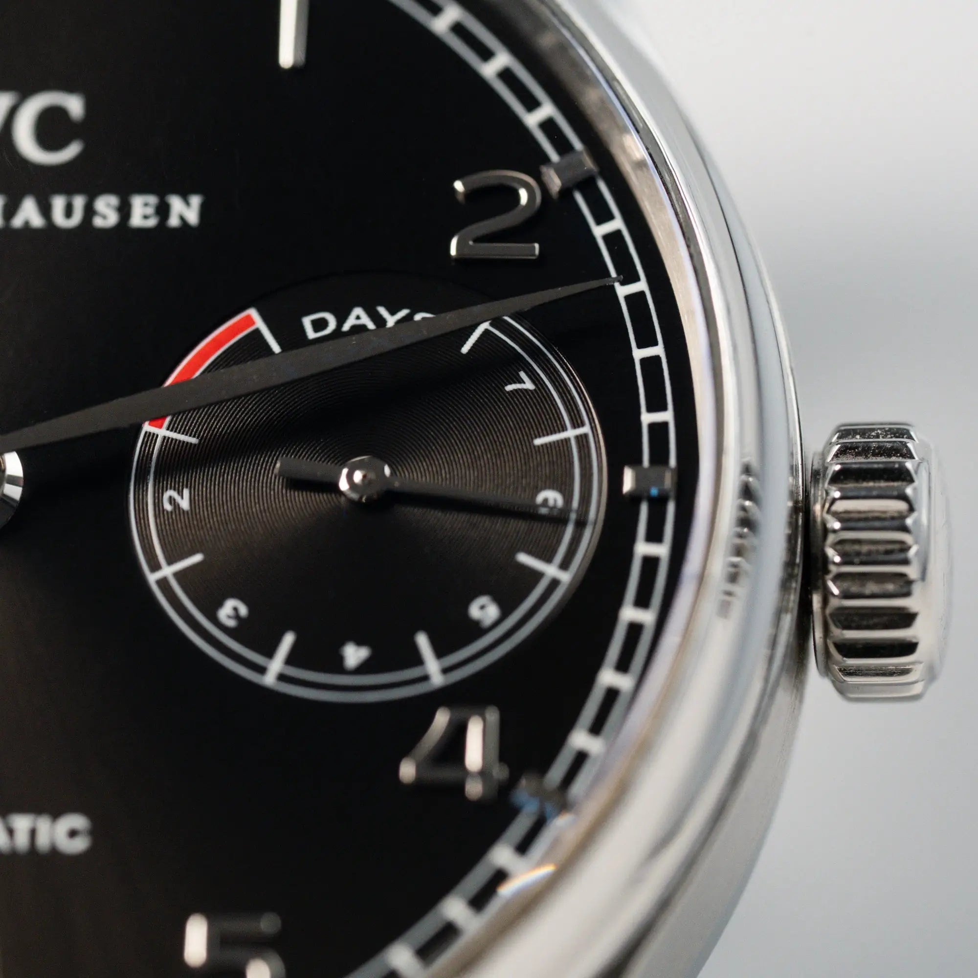 Detailaufnahme der Portugieser 7 Days Automatic IW500109 Uhr von IWC Schaffhausen am schwarzen Lederband mit Fokus auf dem schwarzen Zifferblatt mit 7-Days Powerreserve-Anzeige und dem Edelstahl-Gehäuse