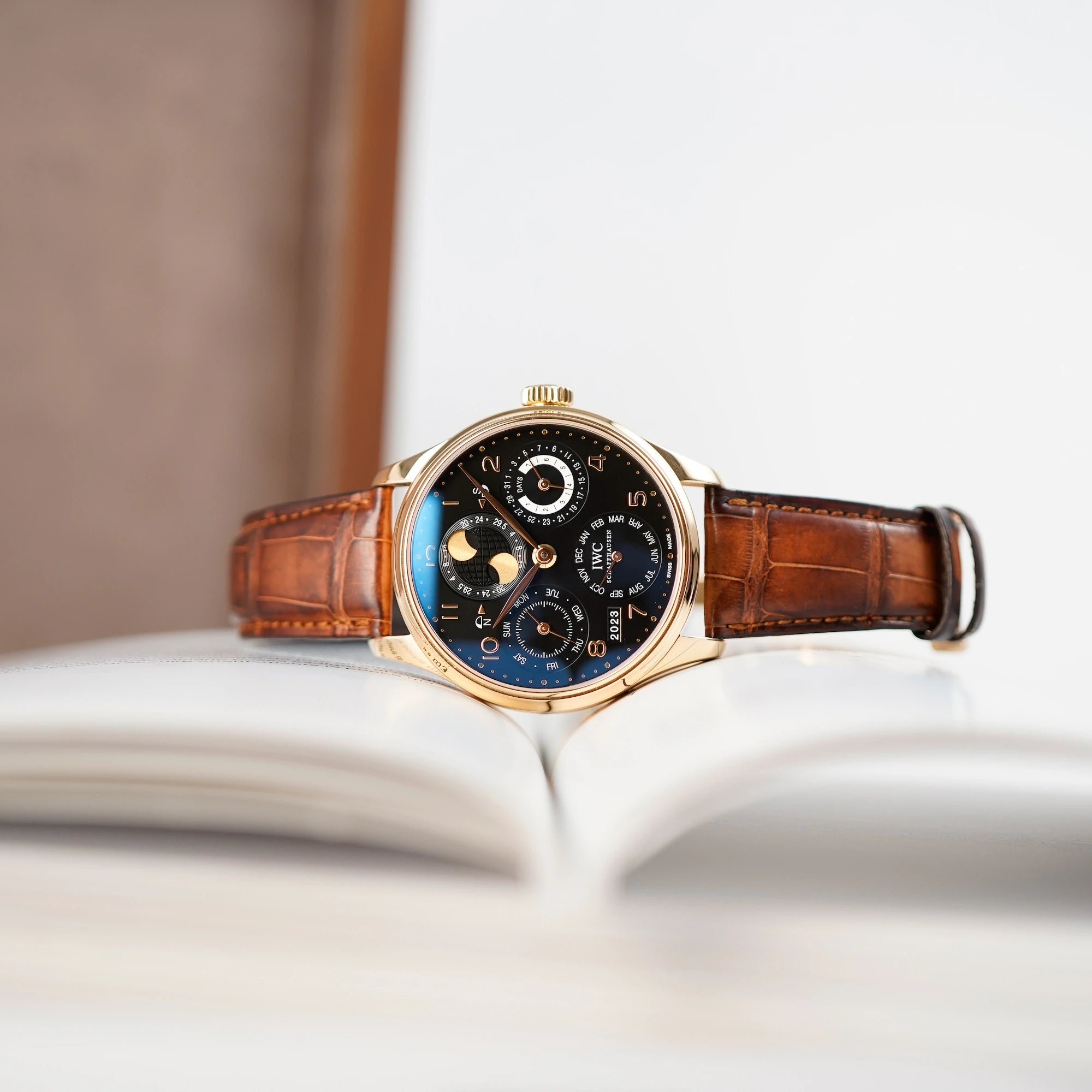 Ewiger Kalender IW502119 in Rotgold von IWC Schaffhausen liegt auf einem geöffnetem Buch mit weißen Seiten