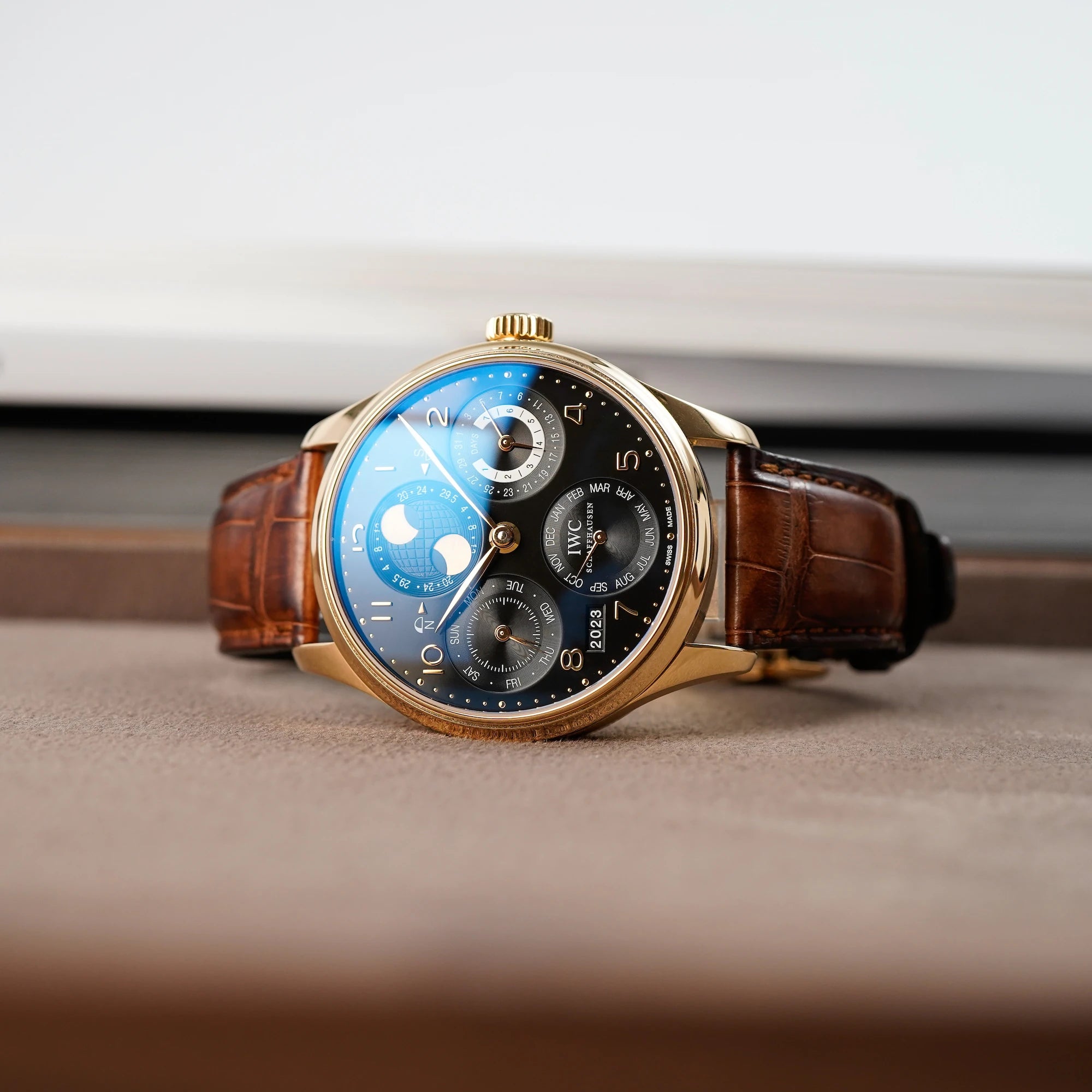 Ewiger Kalender IW502119 in Rotgold von IWC Schaffhausen liegt auf einem Juwelier-Tablet mit hellbraunem Leder