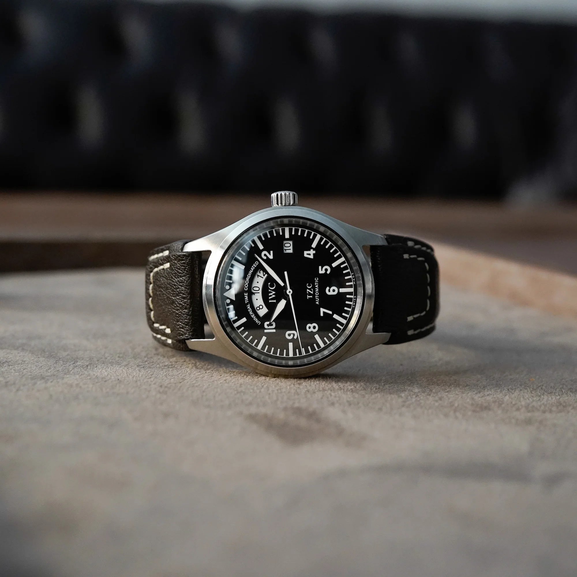 IWC Schaffhausen Pilot Fliegeruhr UTC Spitfire mit der Referenz IW3251 am braunen Lederarmband liegt auf hellbraunem Tablet