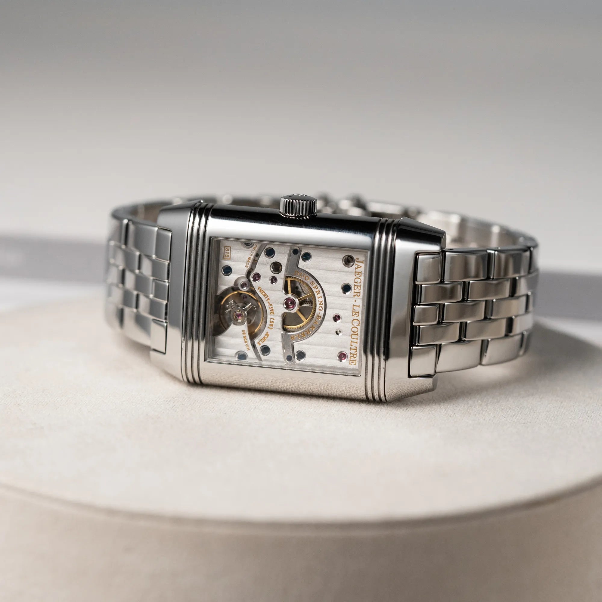 Produktfotografie der Jaeger LeCoultre Reverso Grand Date Armbanduhr mit dem Uhrwerk nach vorne zeigend, dank Reverso-Mechanismus