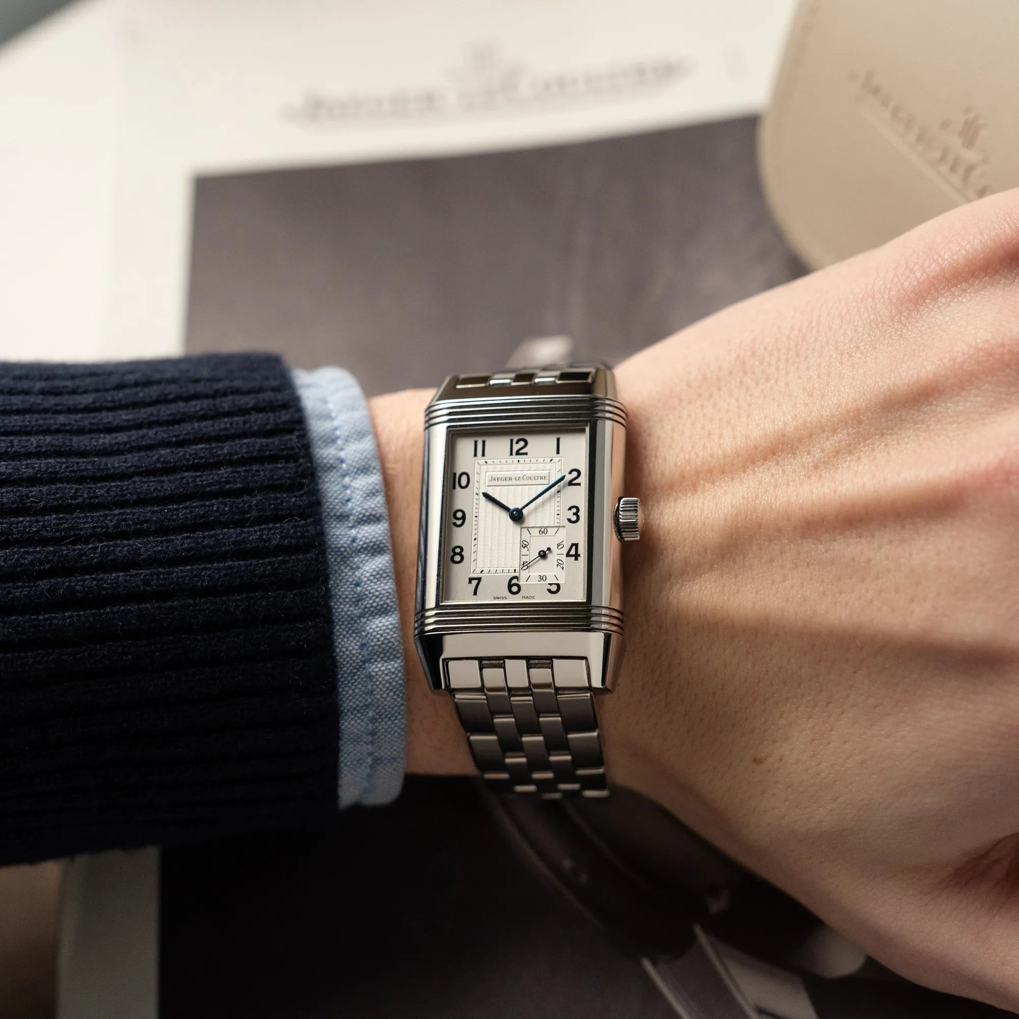 Mann trägt die Jaeger LeCoultre Grand Reverso 8 Armbanduhr am Stahlband mit silbernem Zifferblatt an seinem Handgelenk