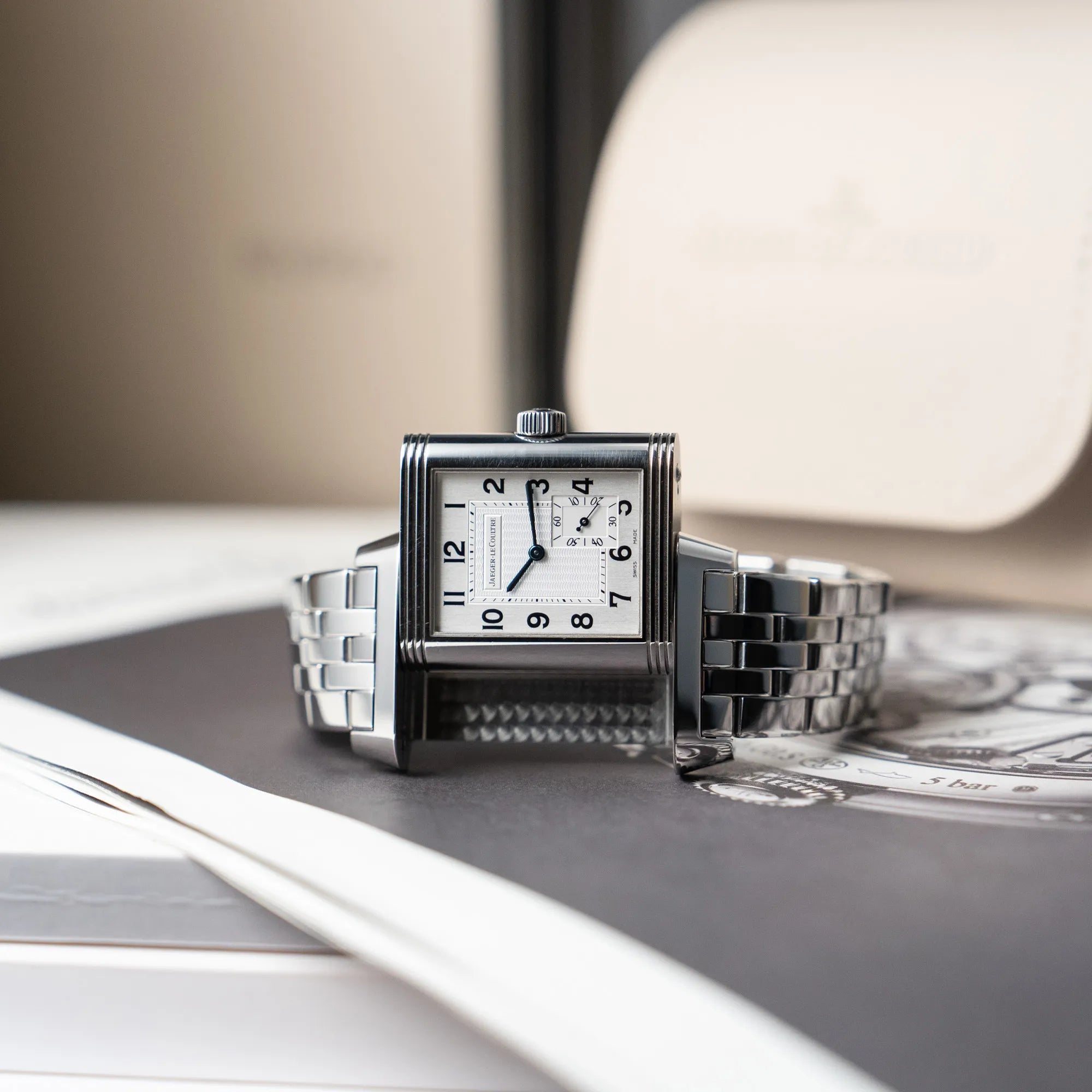 Produktfotografie der Jaeger LeCoultre Grand Reverso 8 am Stahlband mit silbernem Zifferblatt während der Reverso-Mechanismus in Funktion ist
