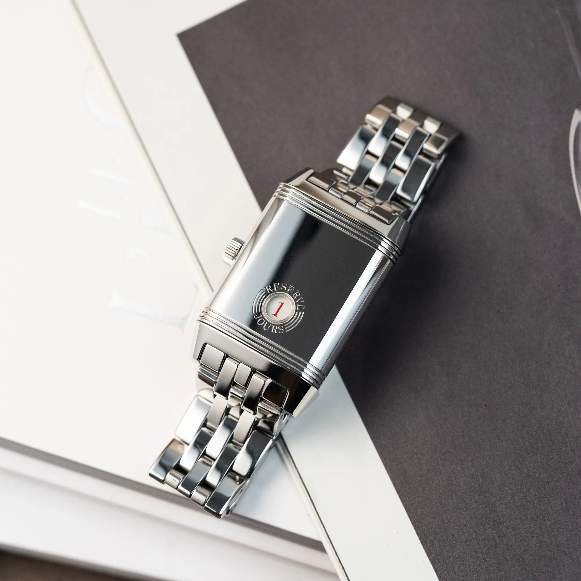 Produktfotografie der Jaeger LeCoultre Grand Reverso 8 am Stahlband mit Blick auf den umgedrehten Gehäuseboden mit der Anzeige der Power-Reserve