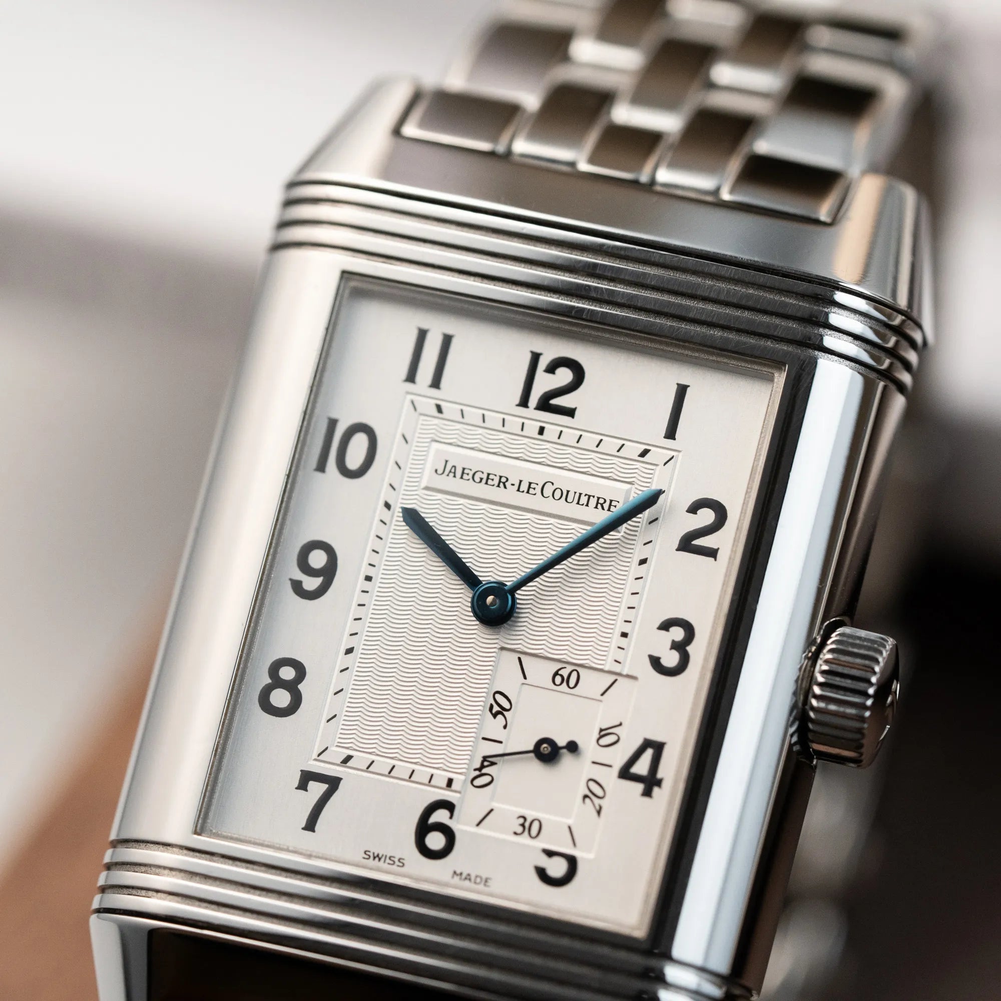 Detailaufnahme der Jaeger LeCoultre Grand Reverso 8 am Stahlband mit silbernem Zifferblatt