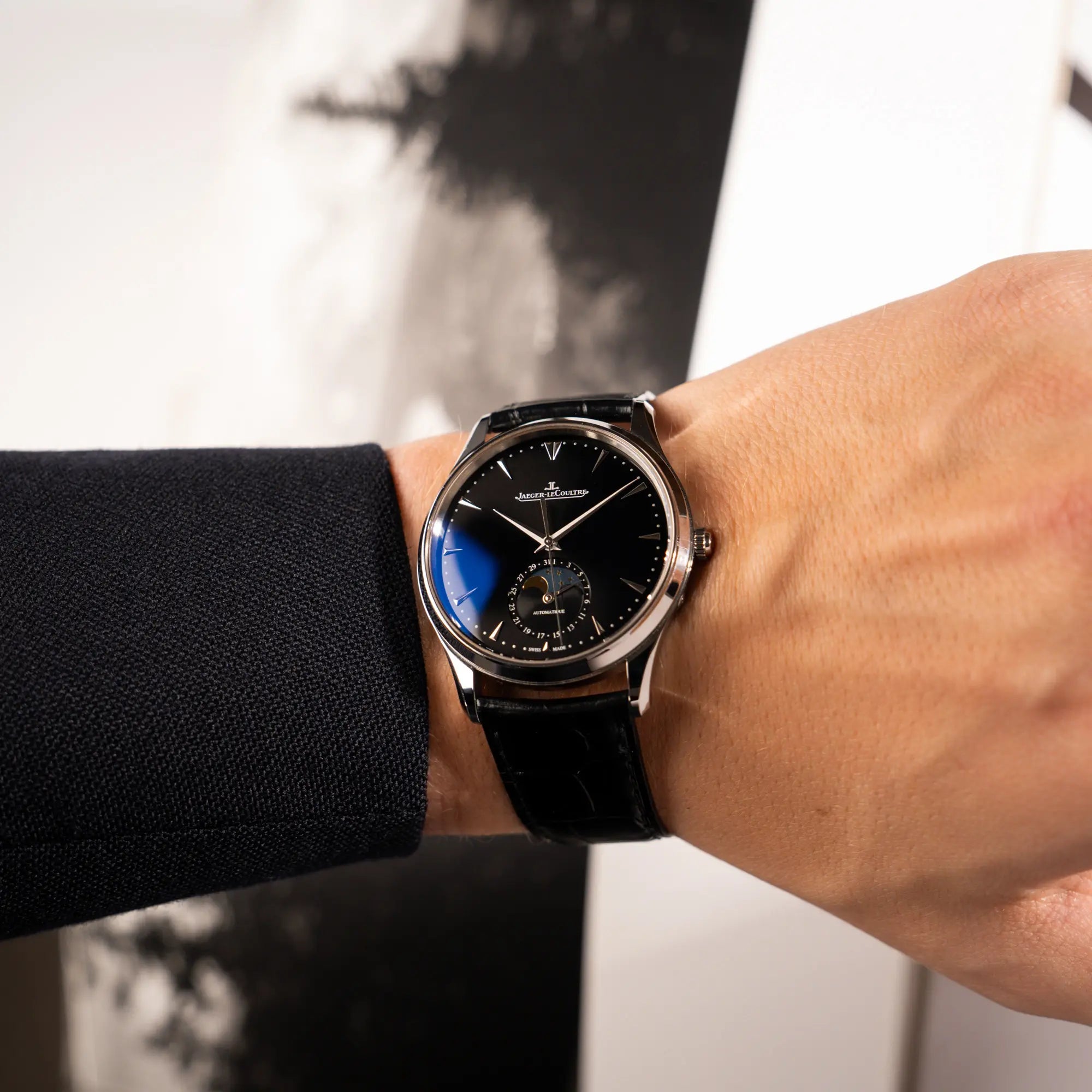 Mann trägt die Jaeger-LeCoultre Master Control Q1368470 mit Datum und Mondphase in der schwarzen Zifferblattvariante an seinem Handgelenk