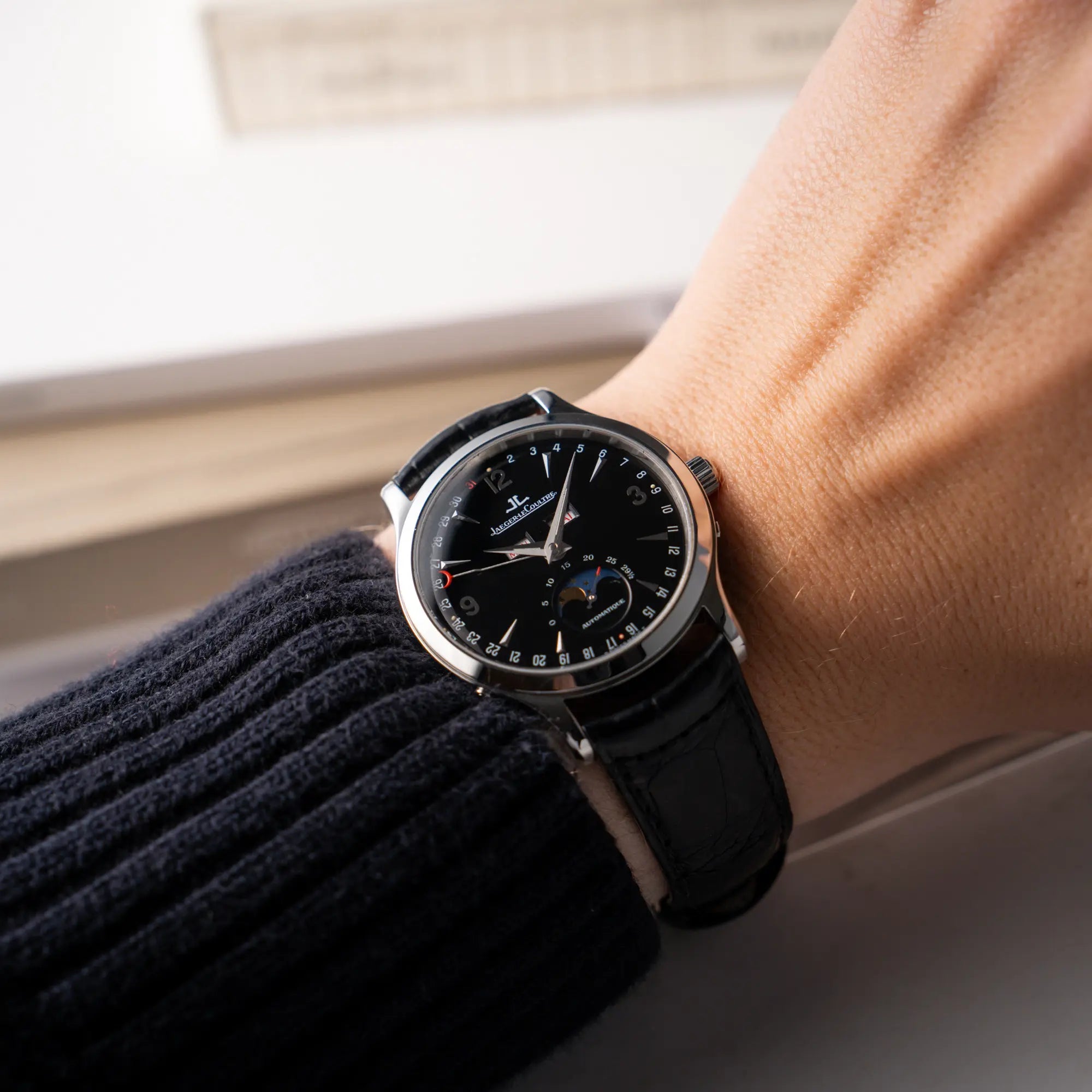 Wristhot mit der Jaeger-LeCoultre Master Control Moonphase Calendar mit schwarzem Zifferblatt am schwarzen Lederband an einem Männerhandgelenk