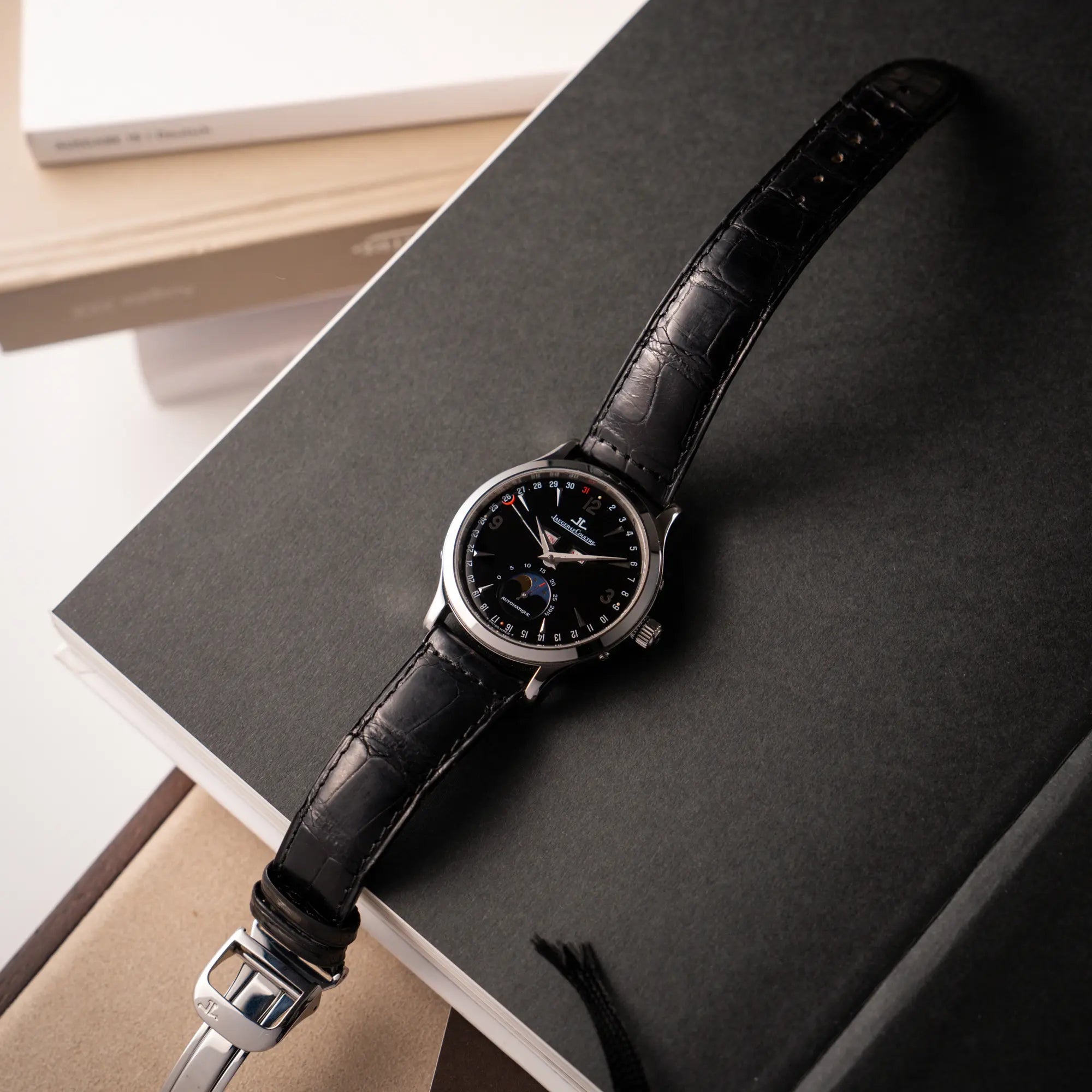 Schöne Produktfotografie der Jaeger-LeCoultre Master Control Moonphase Calendar mit schwarzem Zifferblatt am schwarzen Lederband