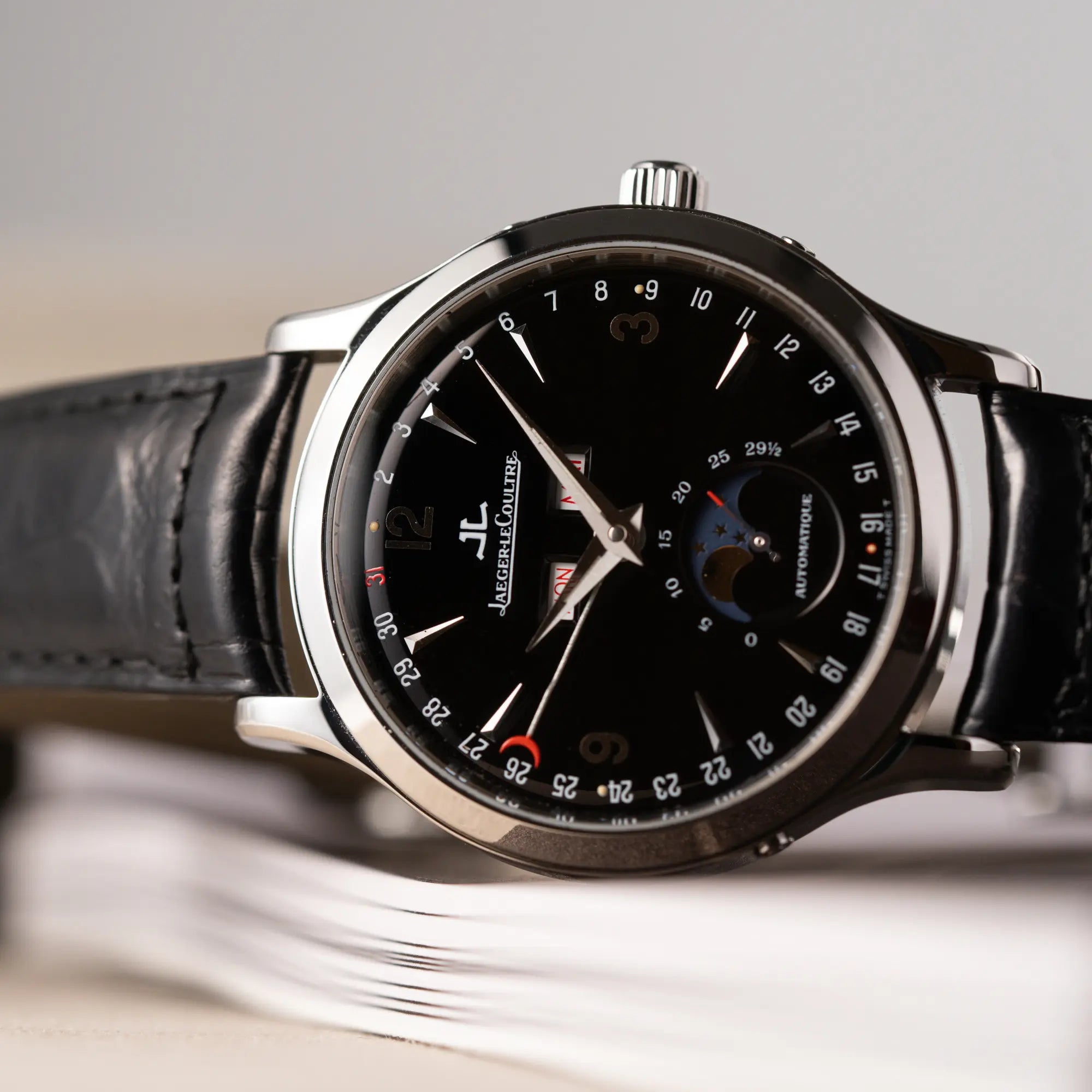Detailaufnahme der seitlich liegenden Jaeger-LeCoultre Master Control Moonphase Calendar mit schwarzem Zifferblatt am schwarzen Lederband