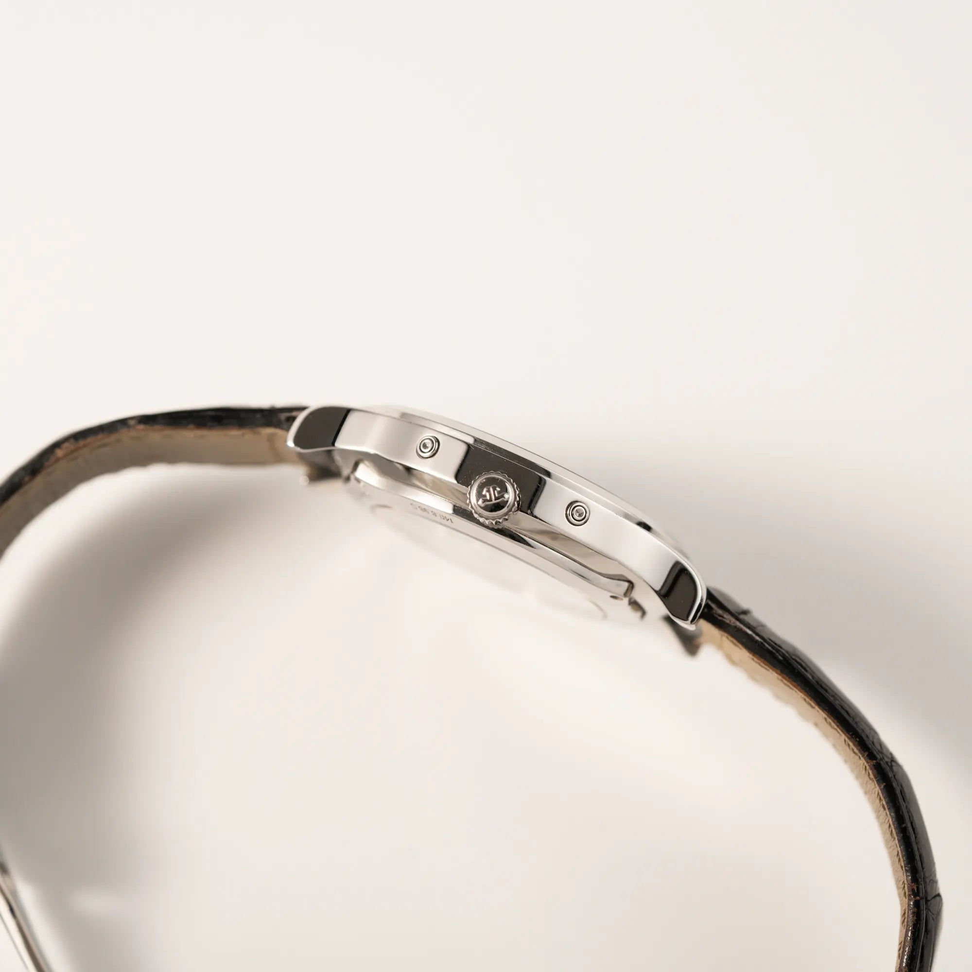 Seitliches Gehäuse der Jaeger-LeCoultre Master Control Moonphase Calendar mit schwarzem Zifferblatt am schwarzen Lederband mit Blick auf die Aufzugskrone