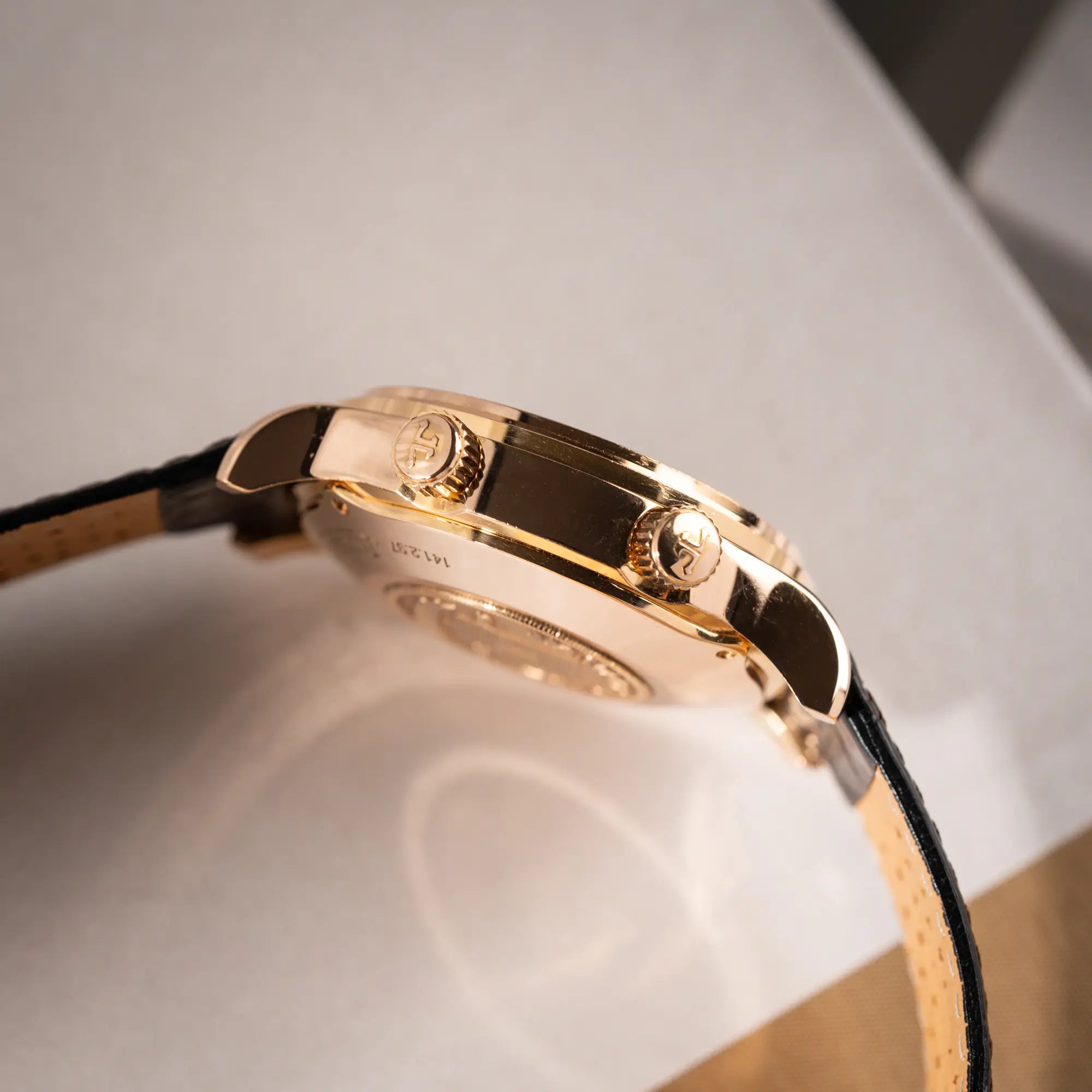 Produktfotografie der Jaeger-LeCoultre Master Memovox 141.2.97 Armbanduhr in Rosegold mit braunem Lederband zeigt die zwei Aufzugskronen