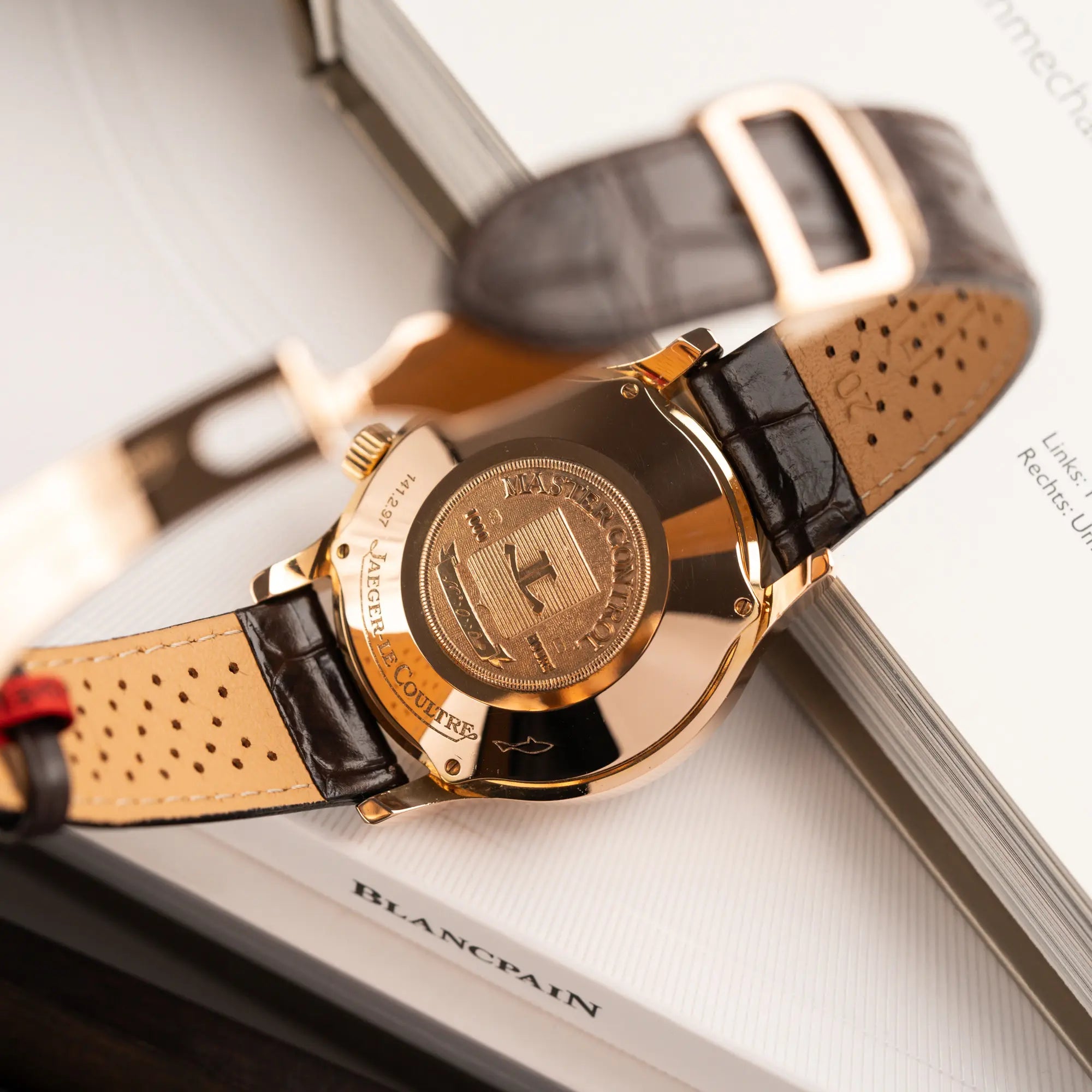 Produktfotografie der Jaeger-LeCoultre Master Memovox 141.2.97 Armbanduhr in Rosegold mit braunem Lederband zeigt den Gehäuseboden