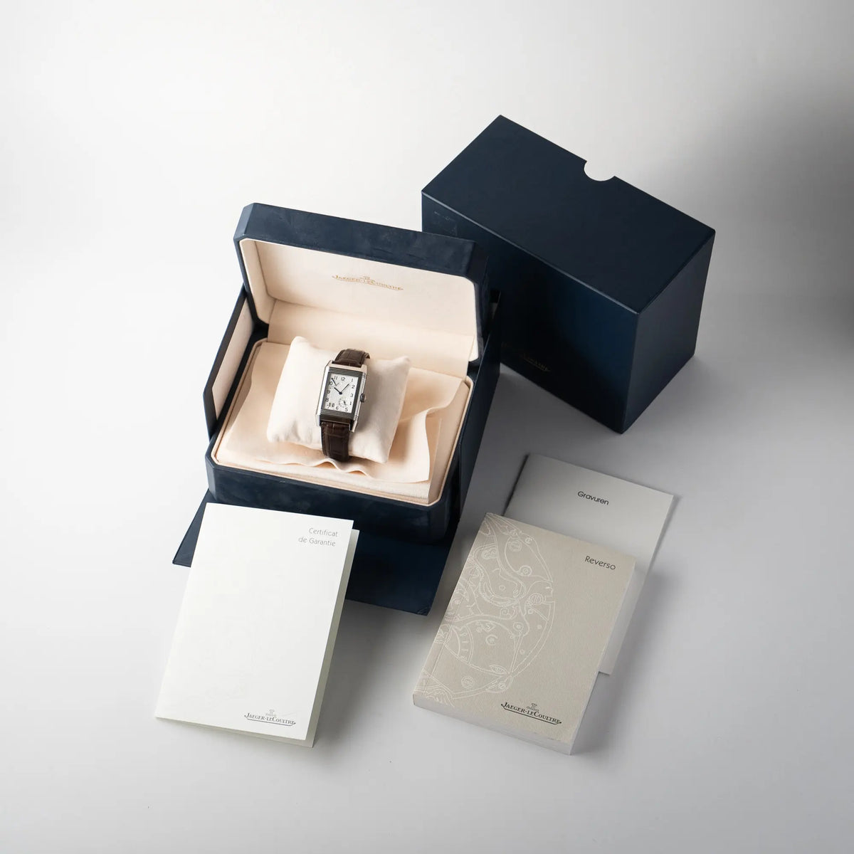Lieferumfang zu der Jaeger-LeCoultre Reverso Grande Date der Referenz 240.8.15 mit silberfarbenem Zifferblatt und Großdatums-Anzeige, kleiner Sekunde und Gangreserve-Anzeige am braunen Lederband, bestehend aus Box mit Umkarton, original Garantiezertifikat (Papiere) und Booklets