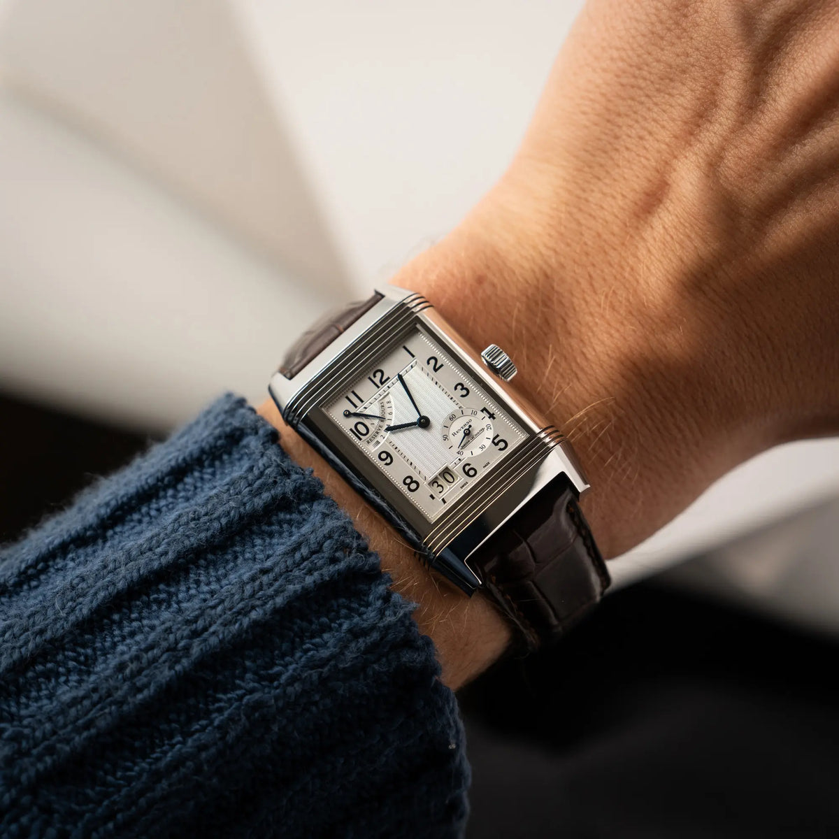 Wristshot mit der Jaeger-LeCoultre Reverso Grande Date der Referenz 240.8.15 mit silberfarbenem Zifferblatt und Großdatums-Anzeige, kleiner Sekunde und Gangreserve-Anzeige am braunen Lederband