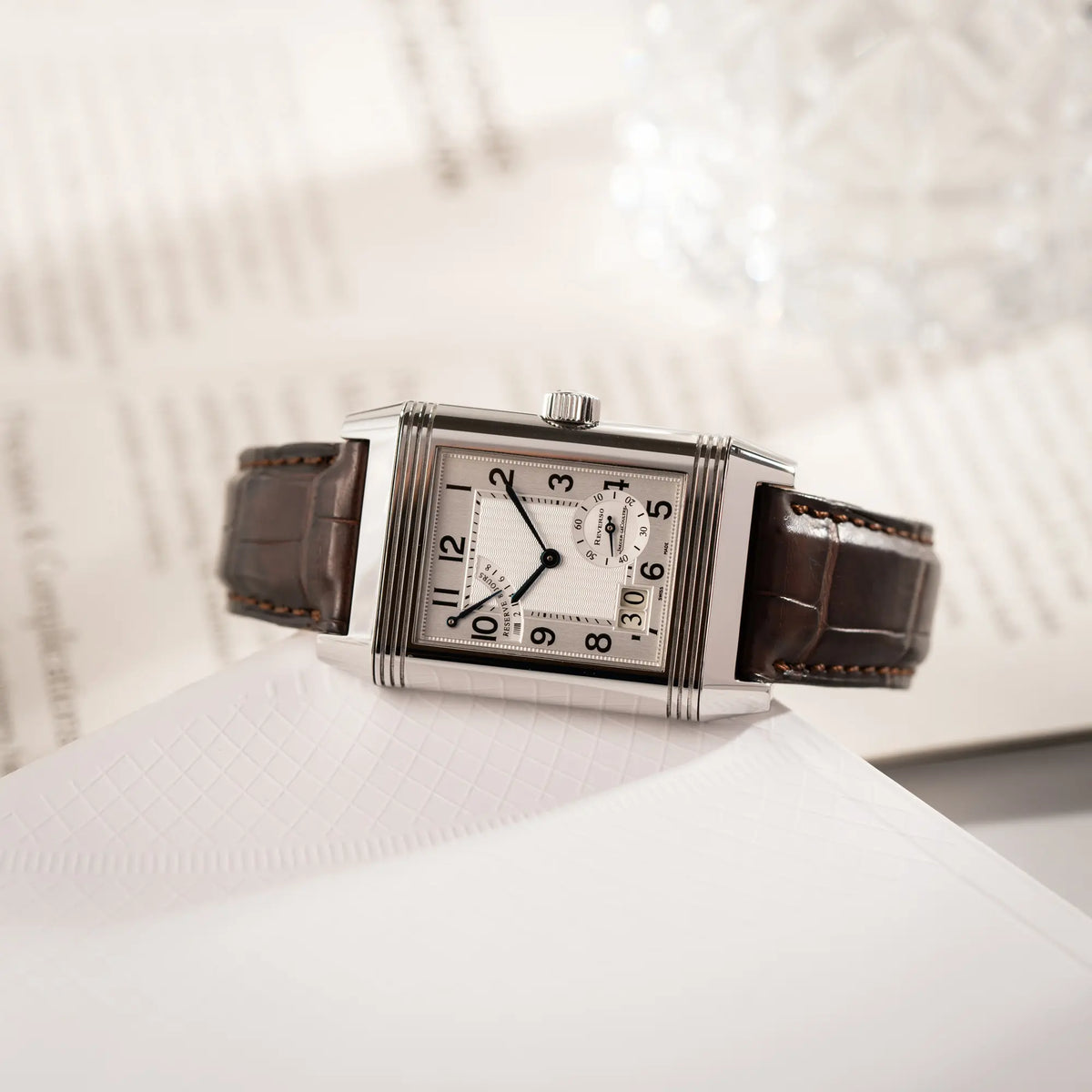 Produktfotografie als Titelbild für doe Jaeger-LeCoultre Reverso Grande Date der Referenz 240.8.15 mit silberfarbenem Zifferblatt und Großdatums-Anzeige, kleiner Sekunde und Gangreserve-Anzeige am braunen Lederband