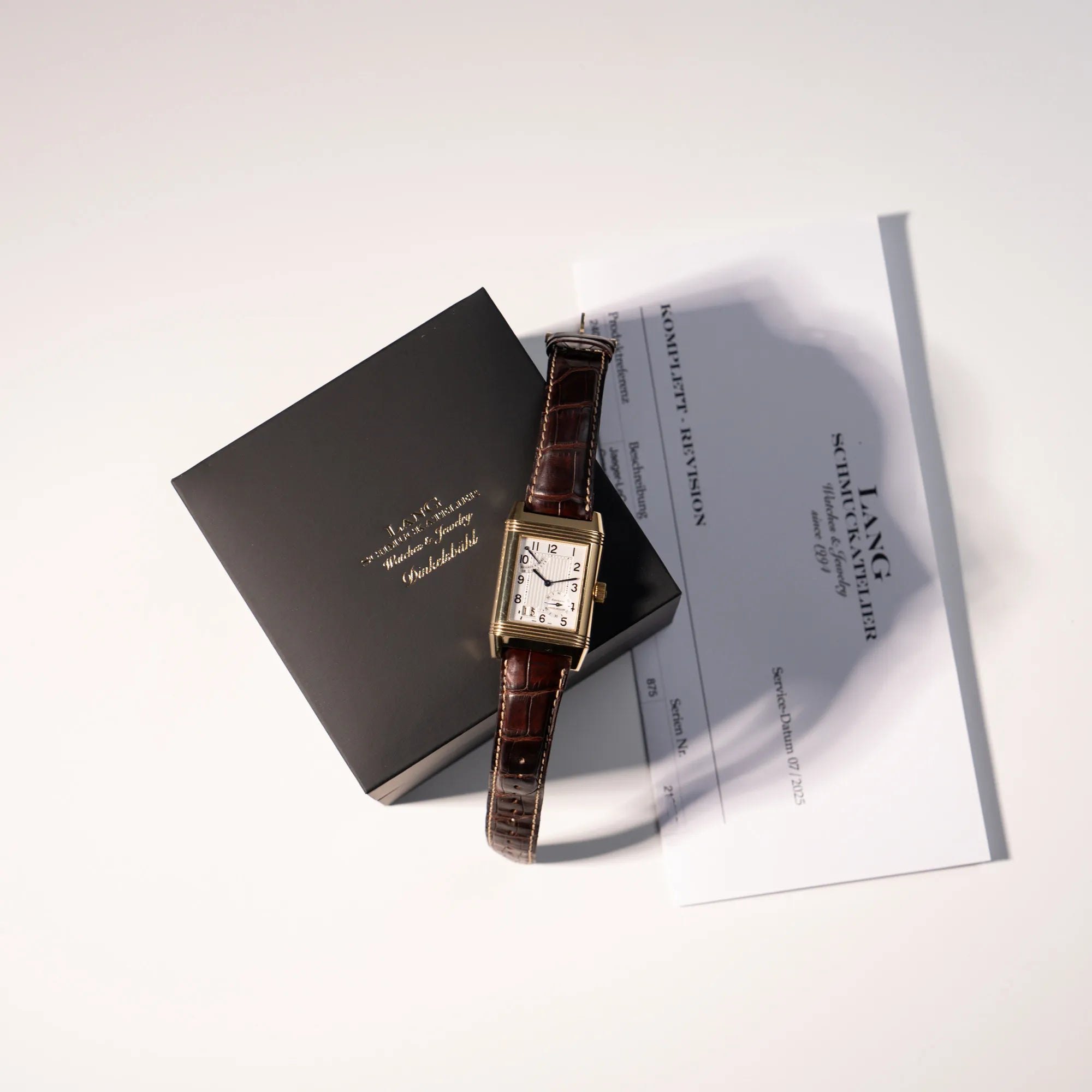 Lieferumfang der Jaeger-LeCoultre Reverso Grande Date der Referenz 240.1.15 mit einem Gelbgold-Gehäuse am braunen Lederband bestehend aus neutraler Box unseres Ateliers und Revisionsbeleg