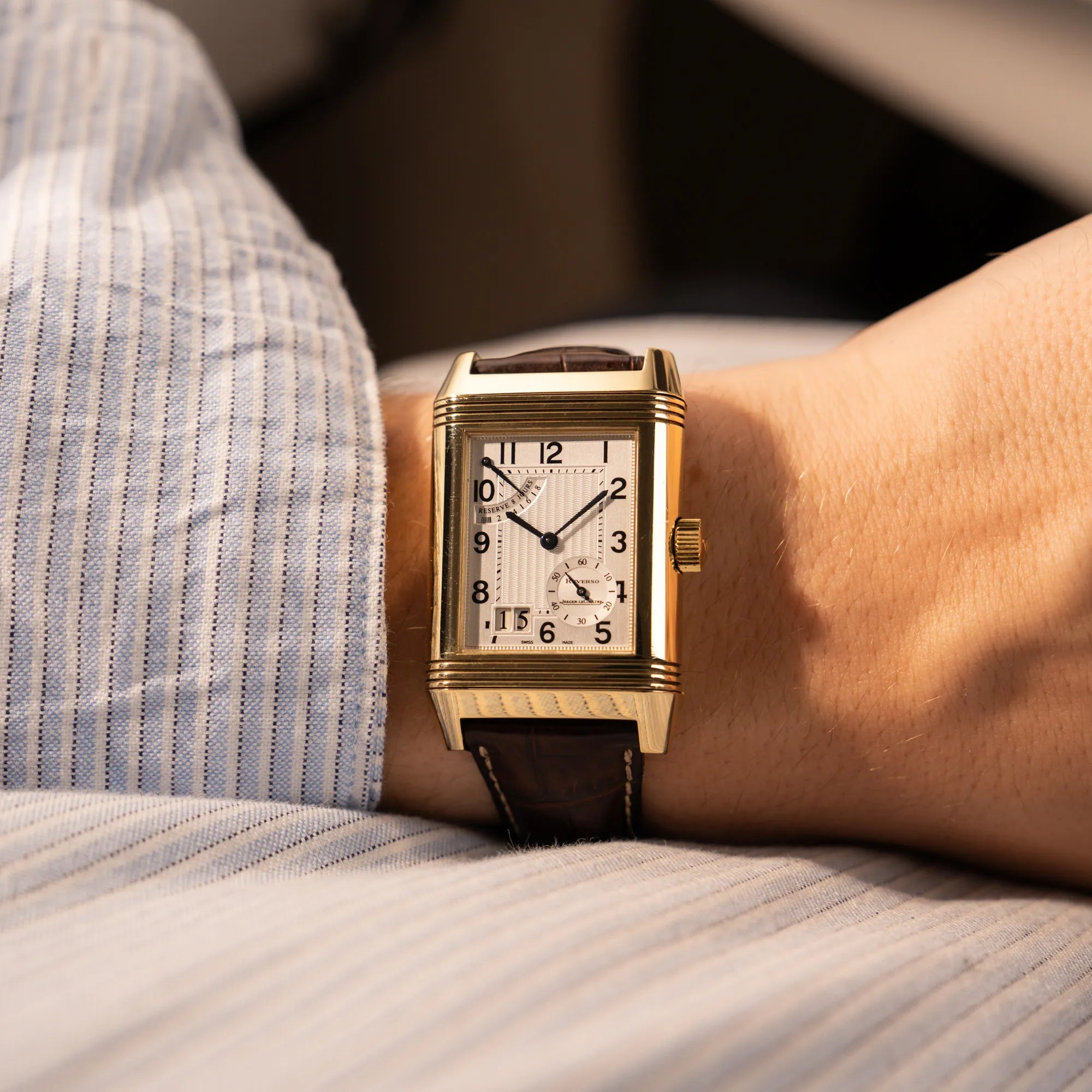 Mann trägt die Jaeger-LeCoultre Reverso Grande Date der Referenz 240.1.15 mit einem Gelbgold-Gehäuse am braunen Lederband an seinem Handgelenk