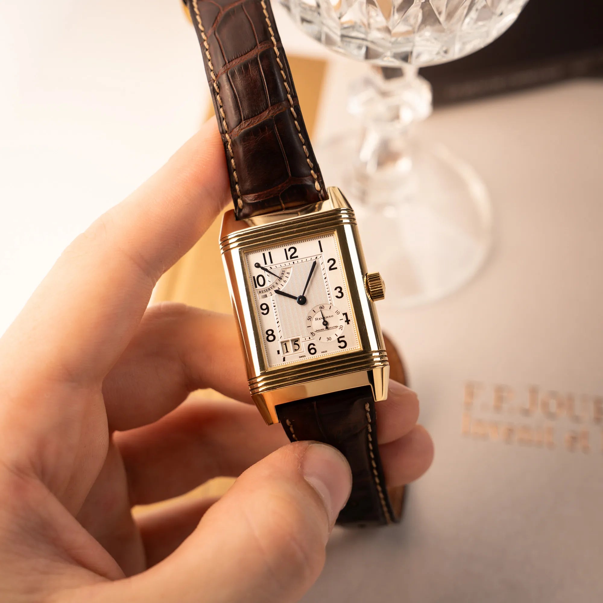 Mann präsentiert die Jaeger-LeCoultre Reverso Grande Date der Referenz 240.1.15 mit einem Gelbgold-Gehäuse am braunen Lederband