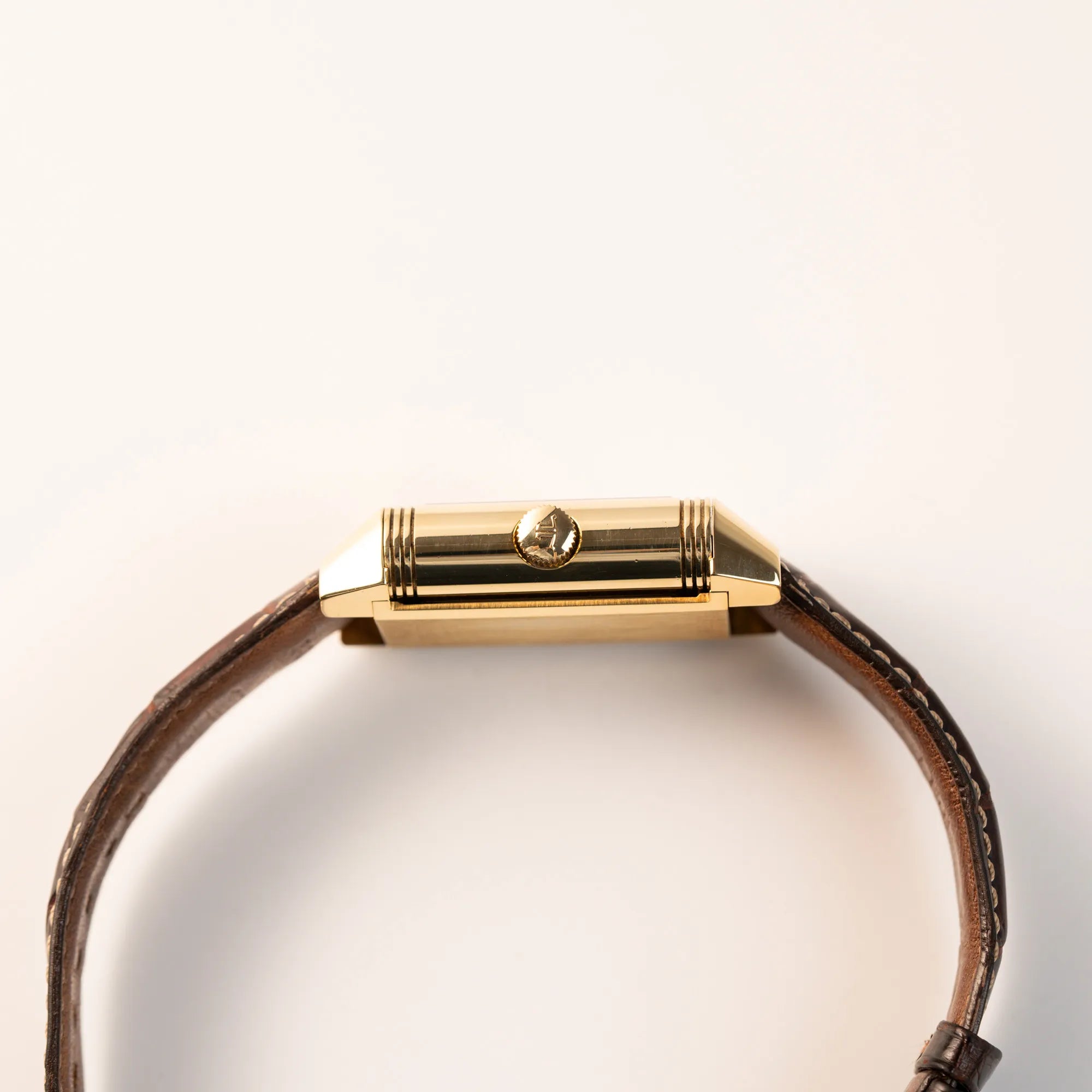 Seitliches Gehäuse der Jaeger-LeCoultre Reverso Grande Date der Referenz 240.1.15 mit einem Gelbgold-Gehäuse am braunen Lederband zeigt die Aufzugskrone
