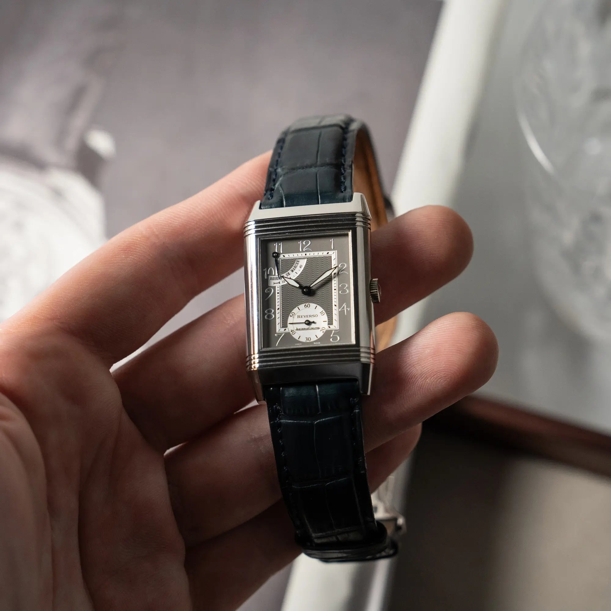 Mann hält die Jaeger LeCoultre Reverso "Reserve de Marche" mit Platingehäuse am Lederband in seiner Hand