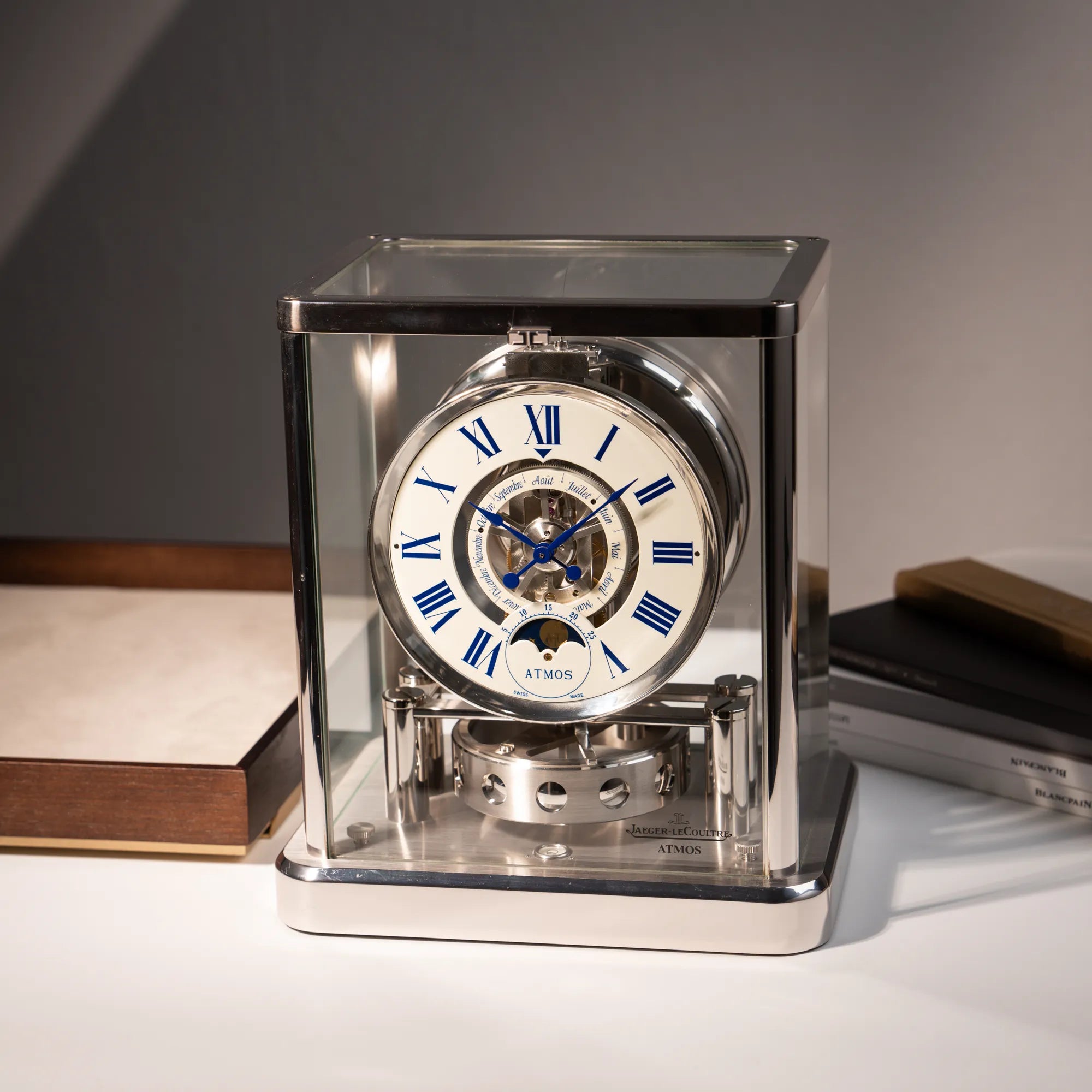 Fotografie der Jaeger-LeCoultre Atmos Mondphase Tischuhr in rhodiniertem Stahl mit weißem Zifferblatt und blauen römischen Indizes