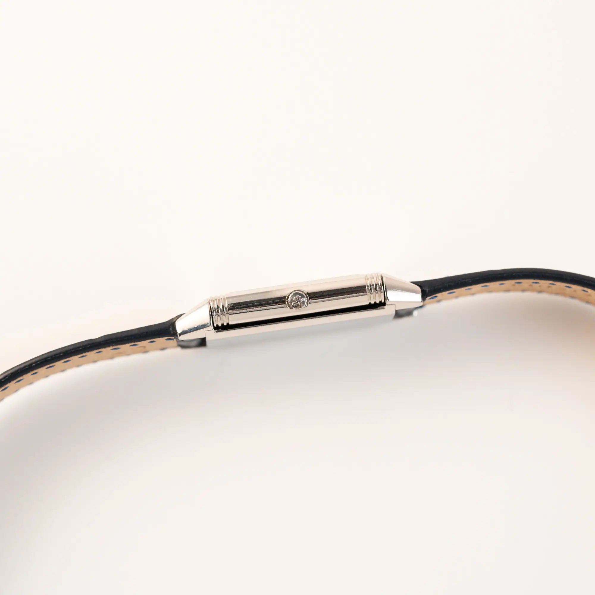 Seitliches Gehäuse der Jaeger-LeCoultre Reverso Classique Medium 250.8.86 in Edelstahl an einem dunkelblauem Lederband mit Blick auf die Aufzugskrone
