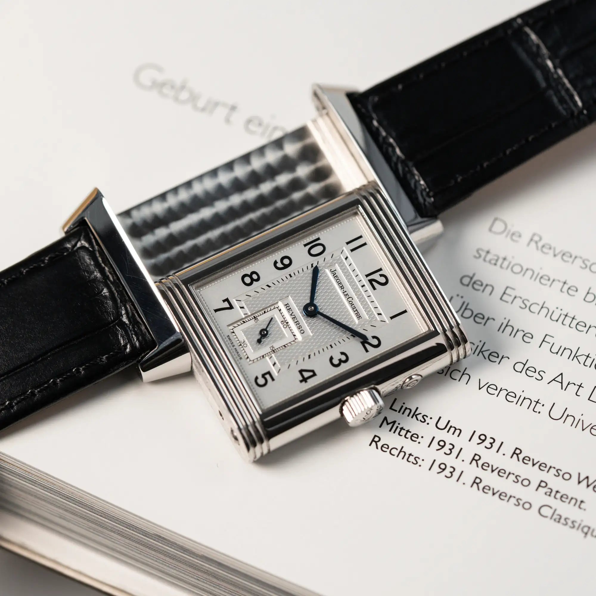 Produktfotografie der Jaeger LeCoultre Reverso Duoface 270.8.54 in Stahl mit Blick auf das weiße Zifferblatt, während der Reverso Mechanismus gezeiugt wird