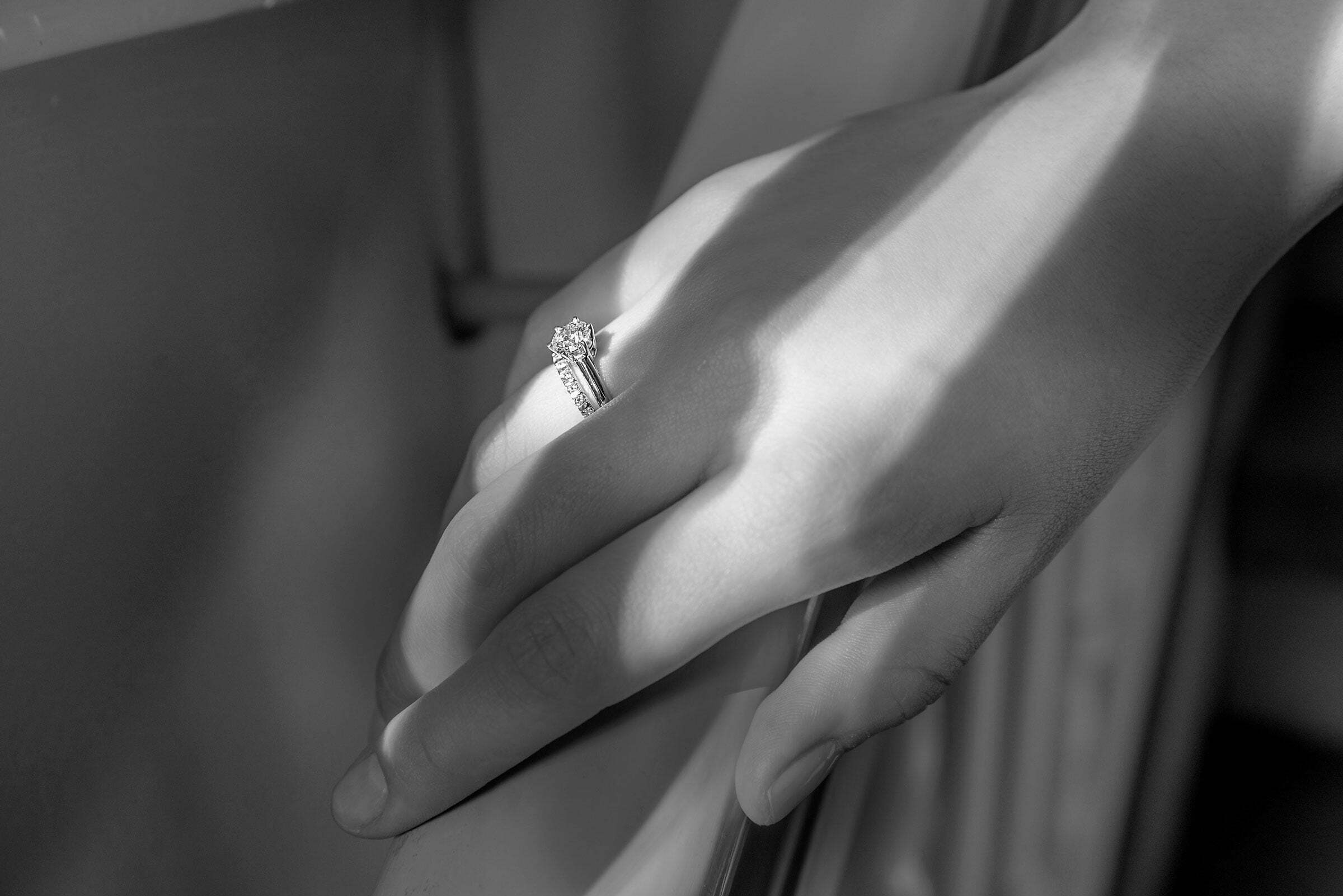 Schwarz-weiß Fotografie einer Frau mit Verlobungsring und Trauring an Ihrem Ringfinger